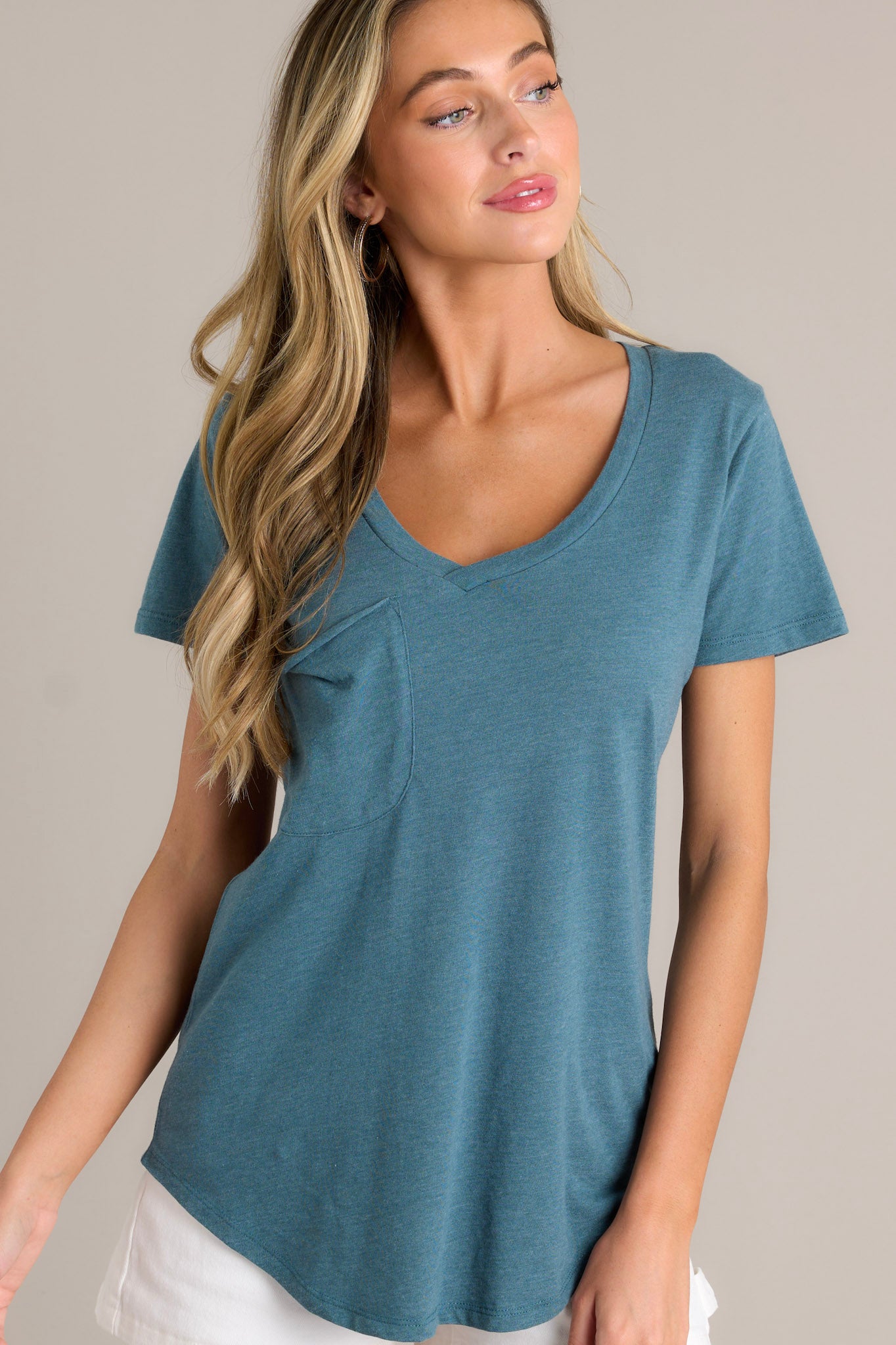 Front angled view of a dragonfly green tee featuring a v-neckline, a functional chest pocket, super soft fabric, and a scooped hemline