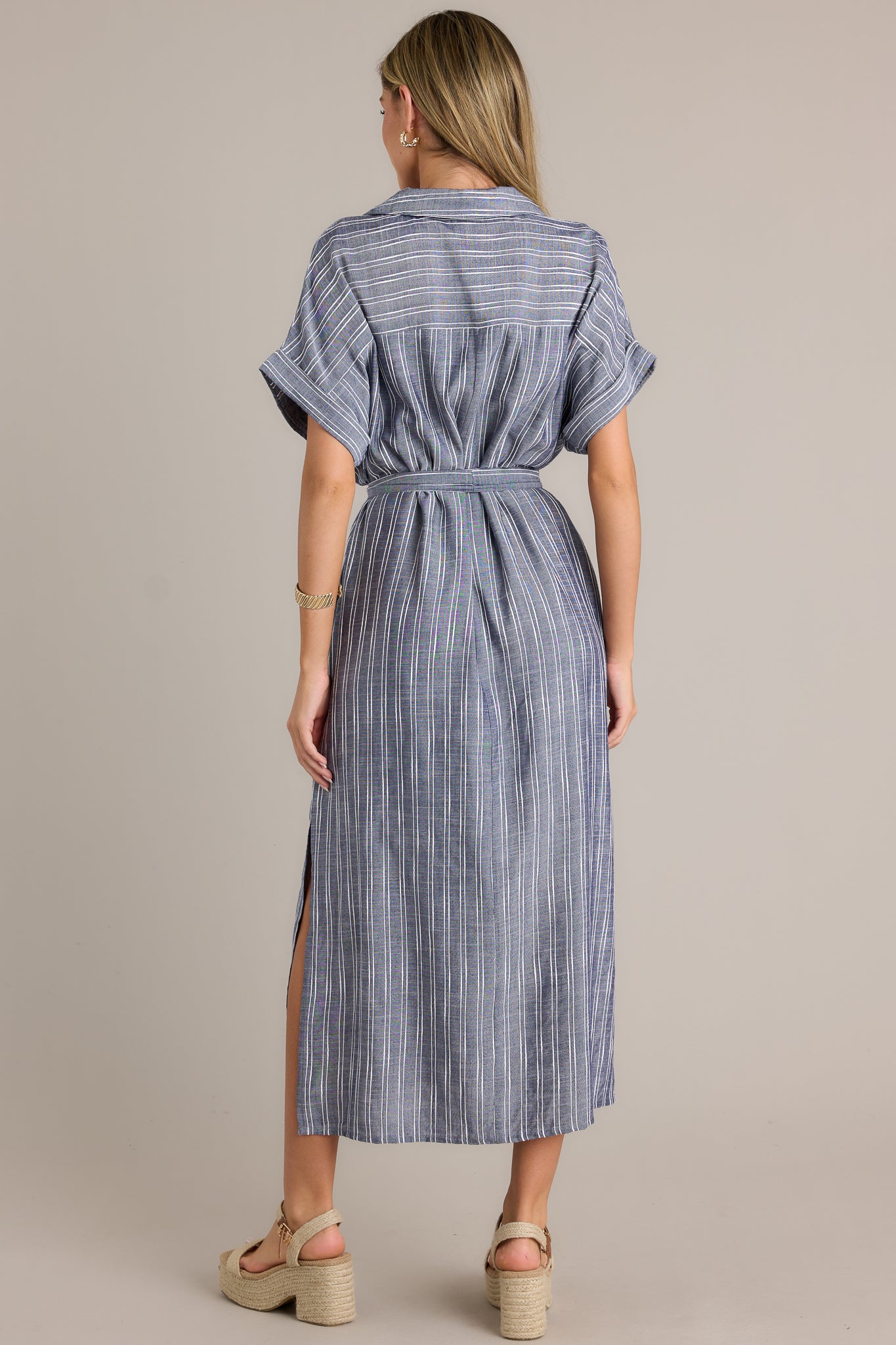 Back view of a blue dress highlighting the overall fit, collared neckline, and cuffed short sleeves.