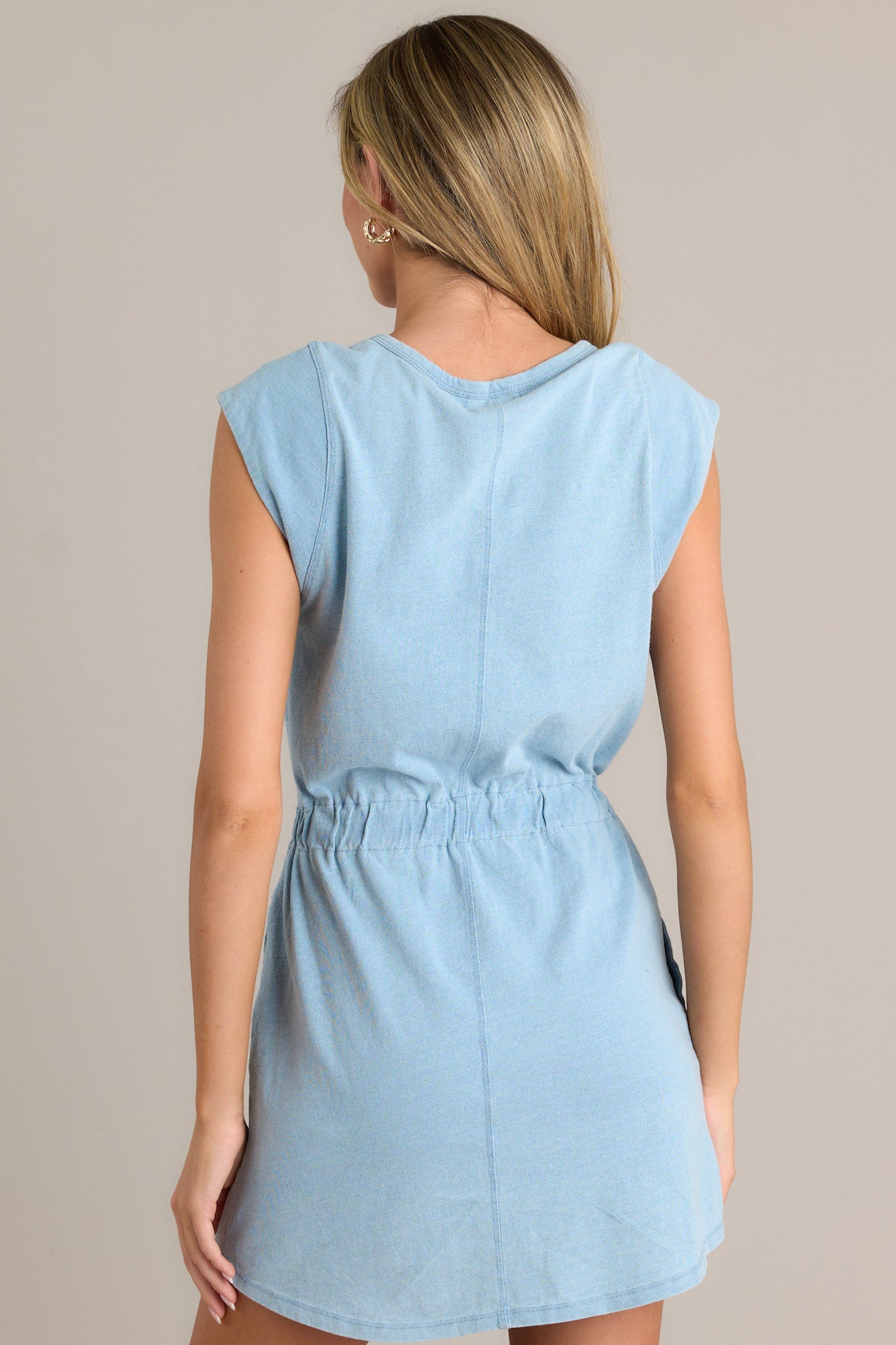 Back view of the washed indigo mini dress highlighting the elastic waistband, the soft fabric, and the simple design at the back.