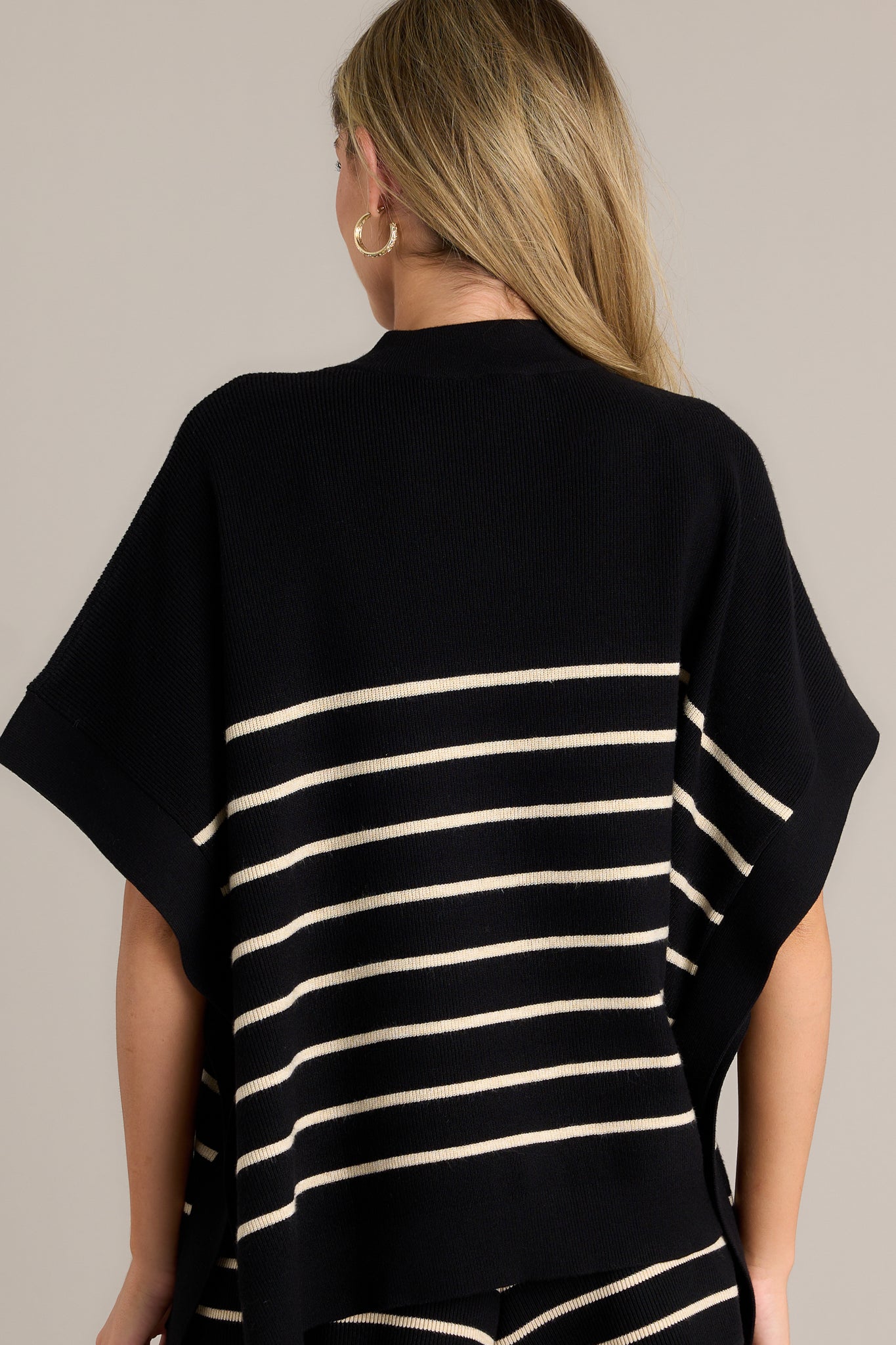 Back view of a stripe poncho top highlighting the overall fit, high side slits, thick hem, and classic stripe design.