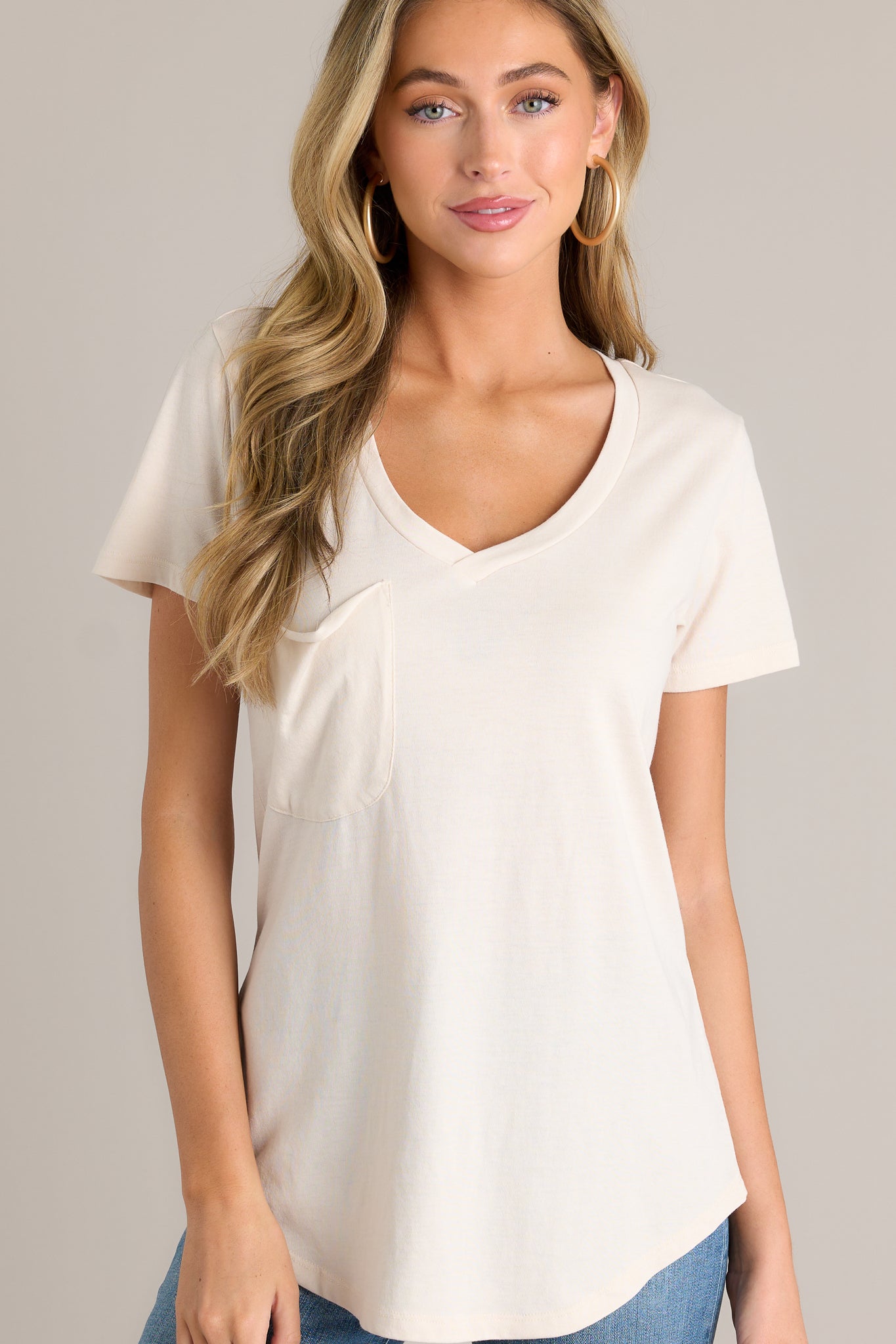 This tee features a v-neckline, a slouched breast pocket, a scooped hemline, and short sleeves.