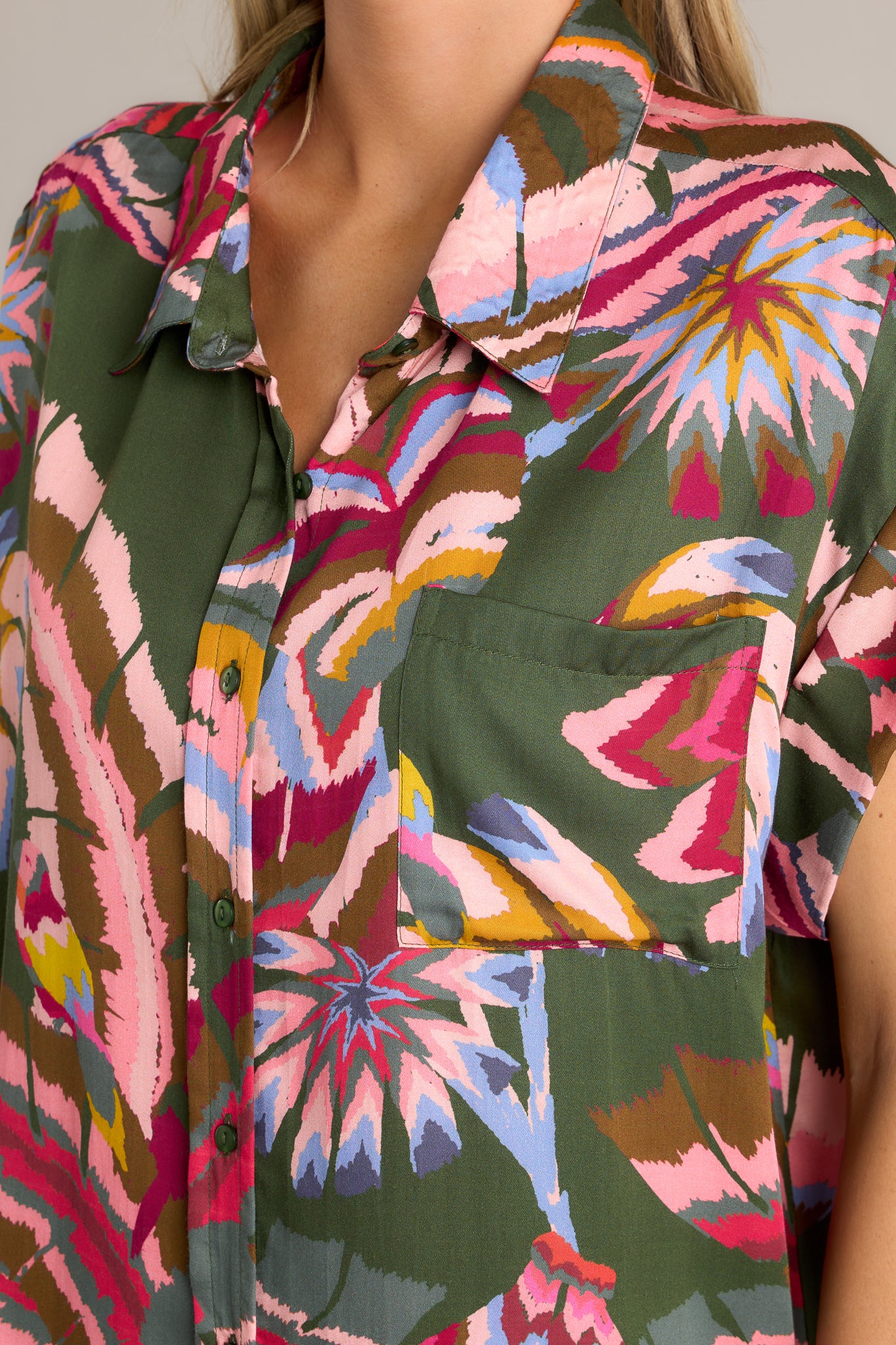 Close-up of the green multi top showing the collared neckline, functional button front, and chest pocket.