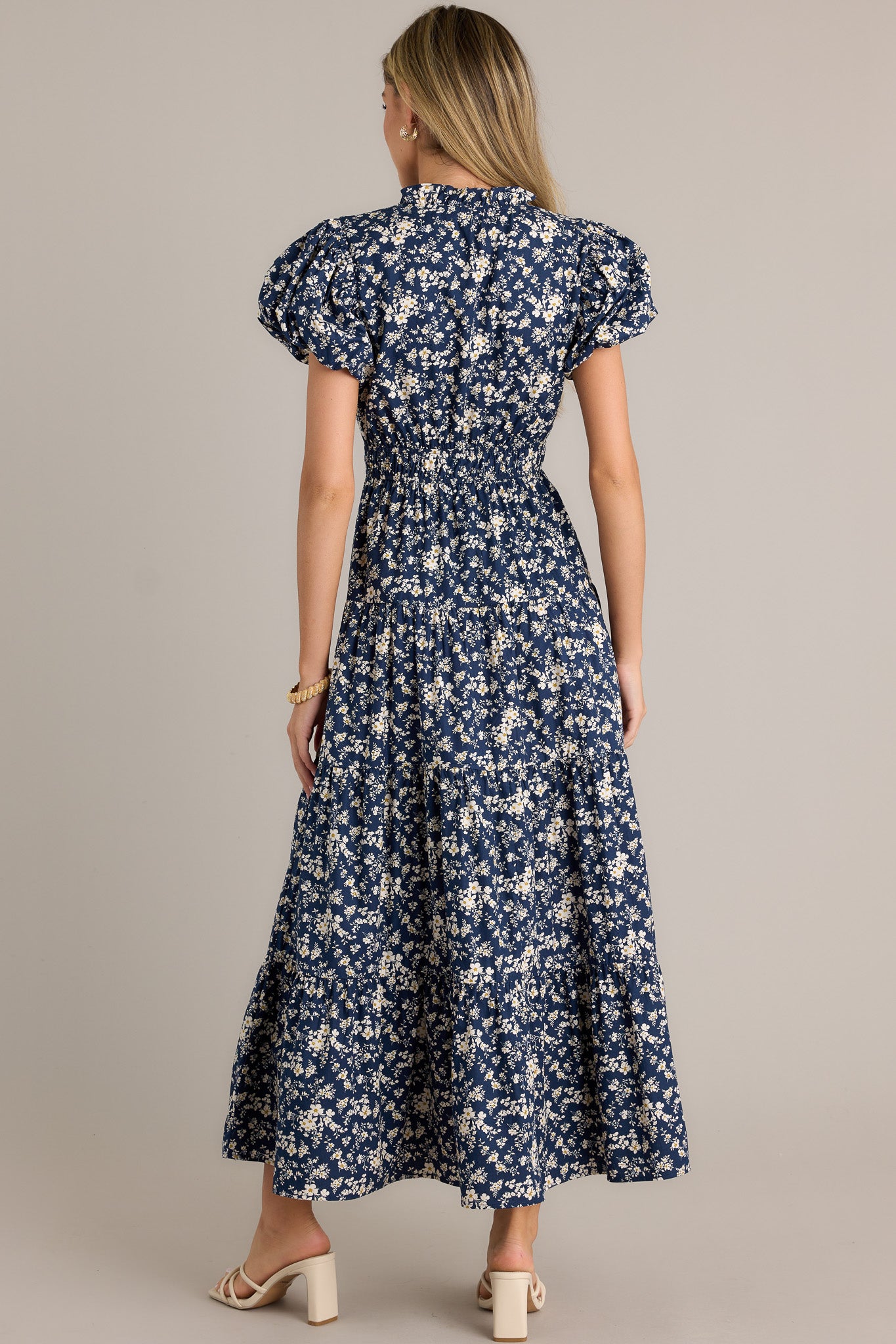 Back view of a navy floral dress highlighting the overall fit, tiered design, and flowing silhouette.