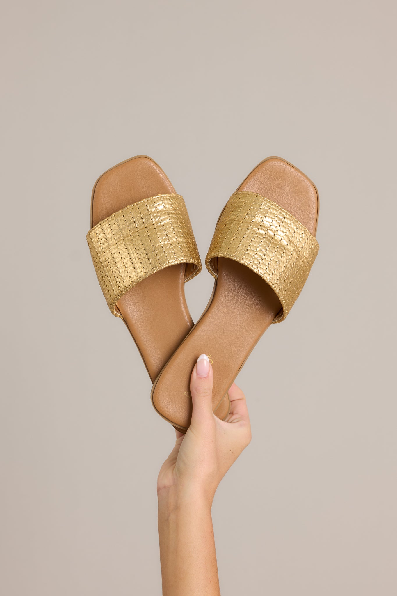 Overhead view of these sandals featuring a gold detailed strap over the foot and a slip-on style.