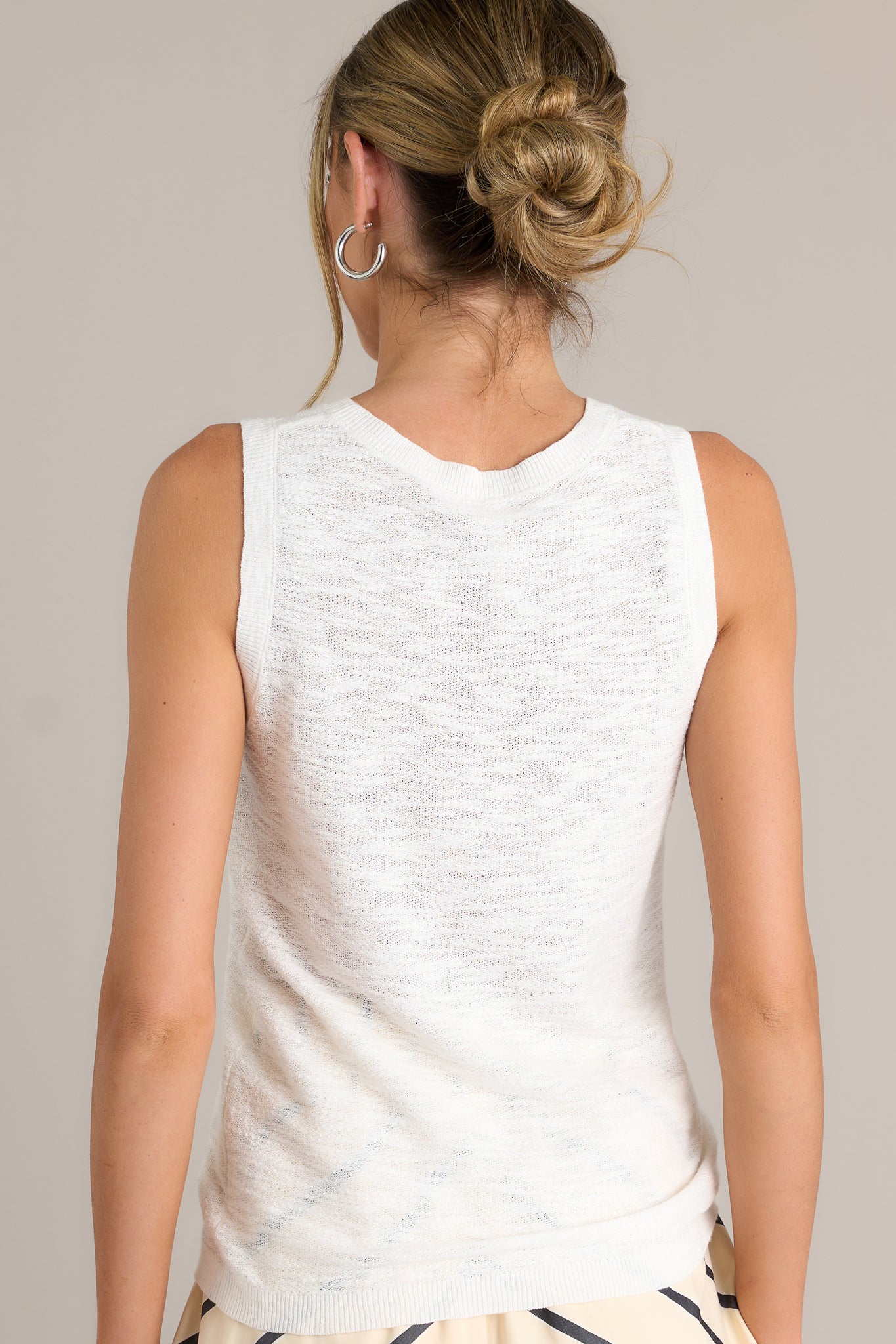 Back view of this top that features a high round neckline, a sleeveless design, a high back, ribbed texture around the hemlines, and a light breathable fabric.