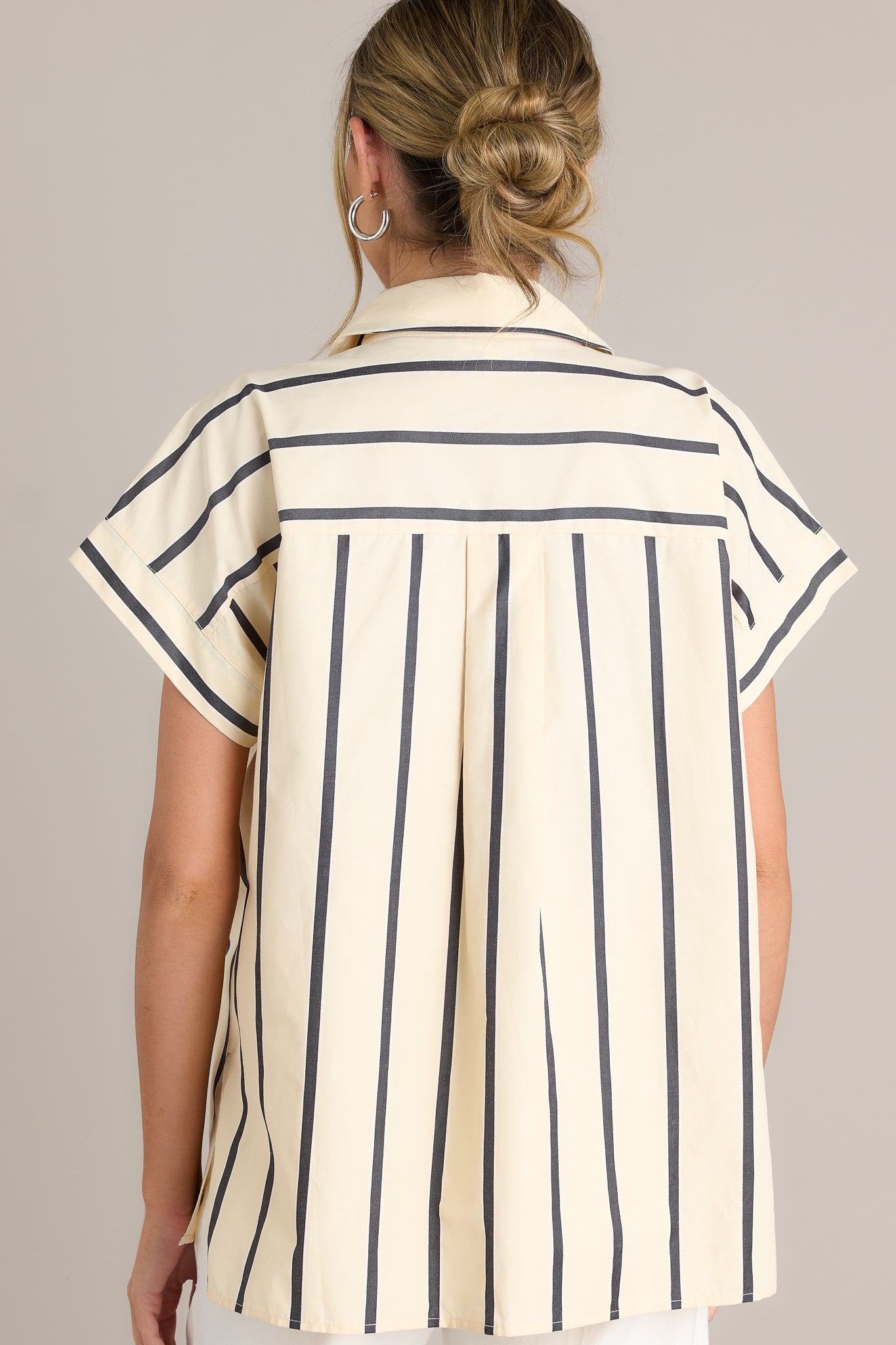 Back view of a black stripe top highlighting the overall fit, split hemline, and short sleeves.