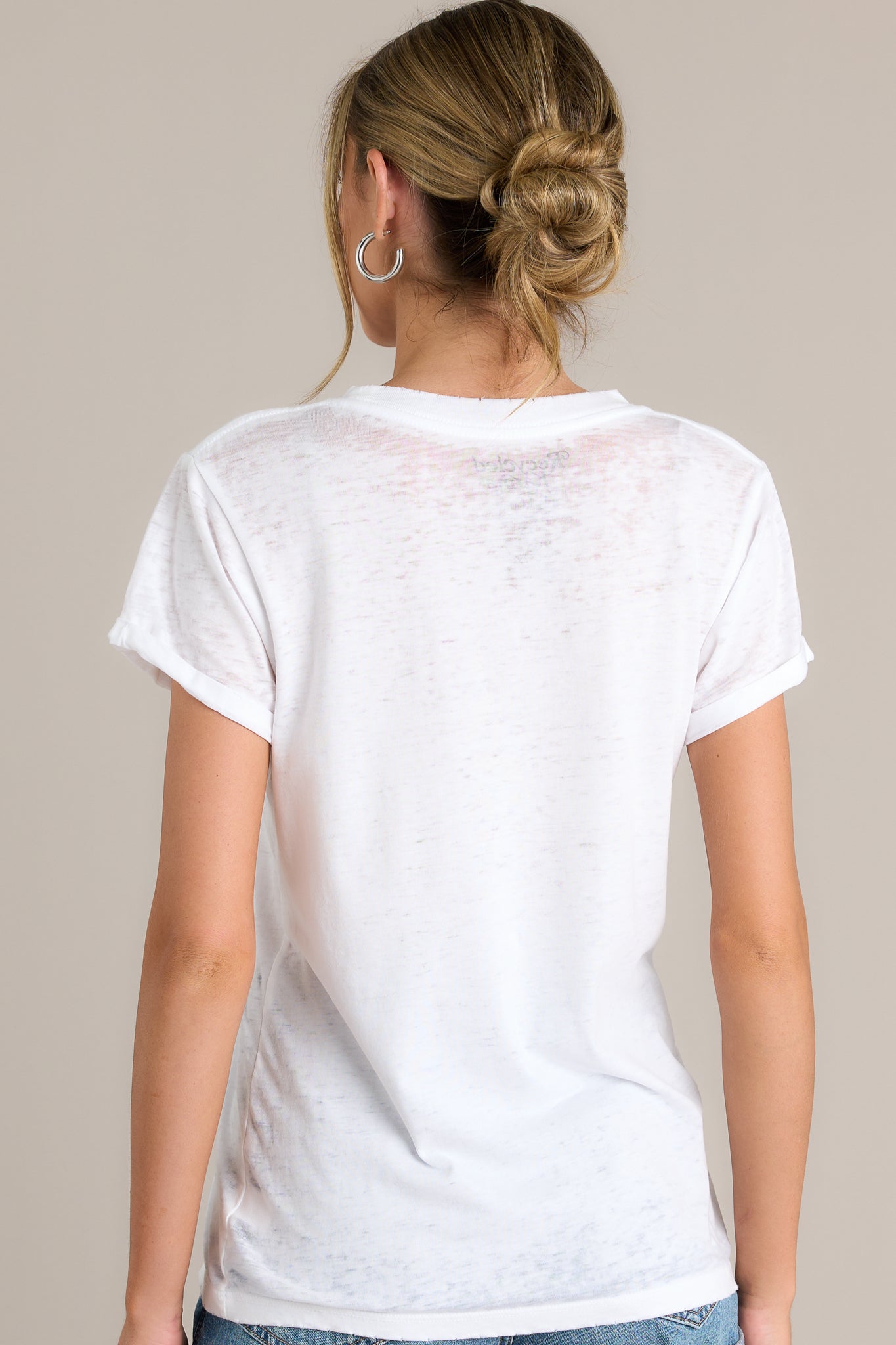 Back view of a tee highlighting the vintage distressing on the hemlines, soft breathable fabric, and rolled up short sleeves.