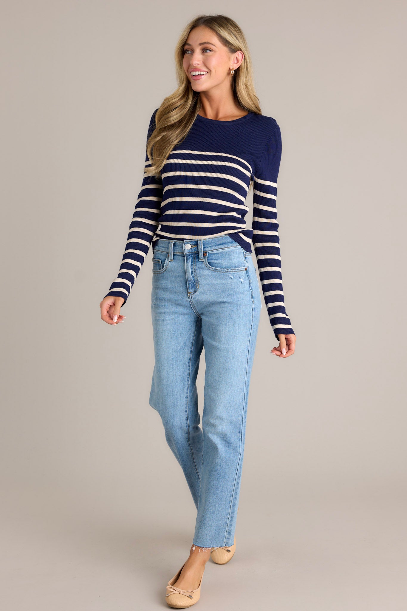 Action shot of a beige stripe navy top displaying the fit and movement, highlighting the crew neckline, stretchy ribbed fabric, striped pattern, and long sleeves.