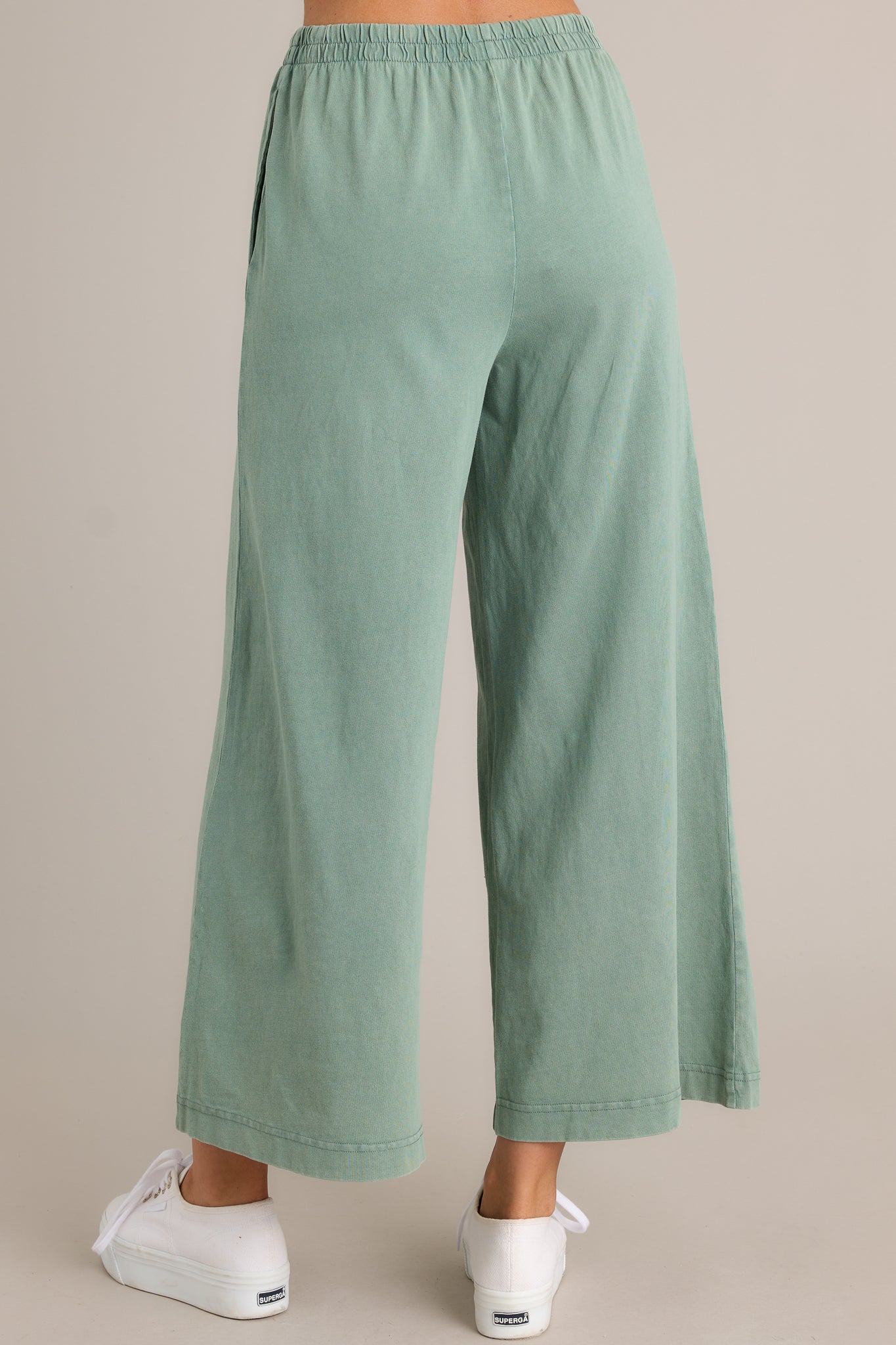 Back view of green flare pants highlighting the overall fit, elastic waistband, and wide leg design.