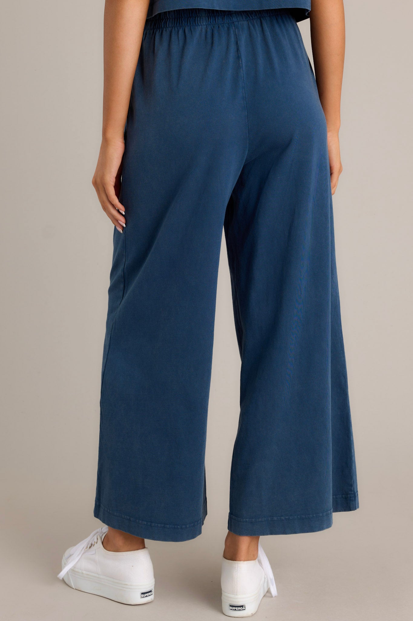 Back view of blue flare pants highlighting the overall fit, wide leg design, and soft jersey material.