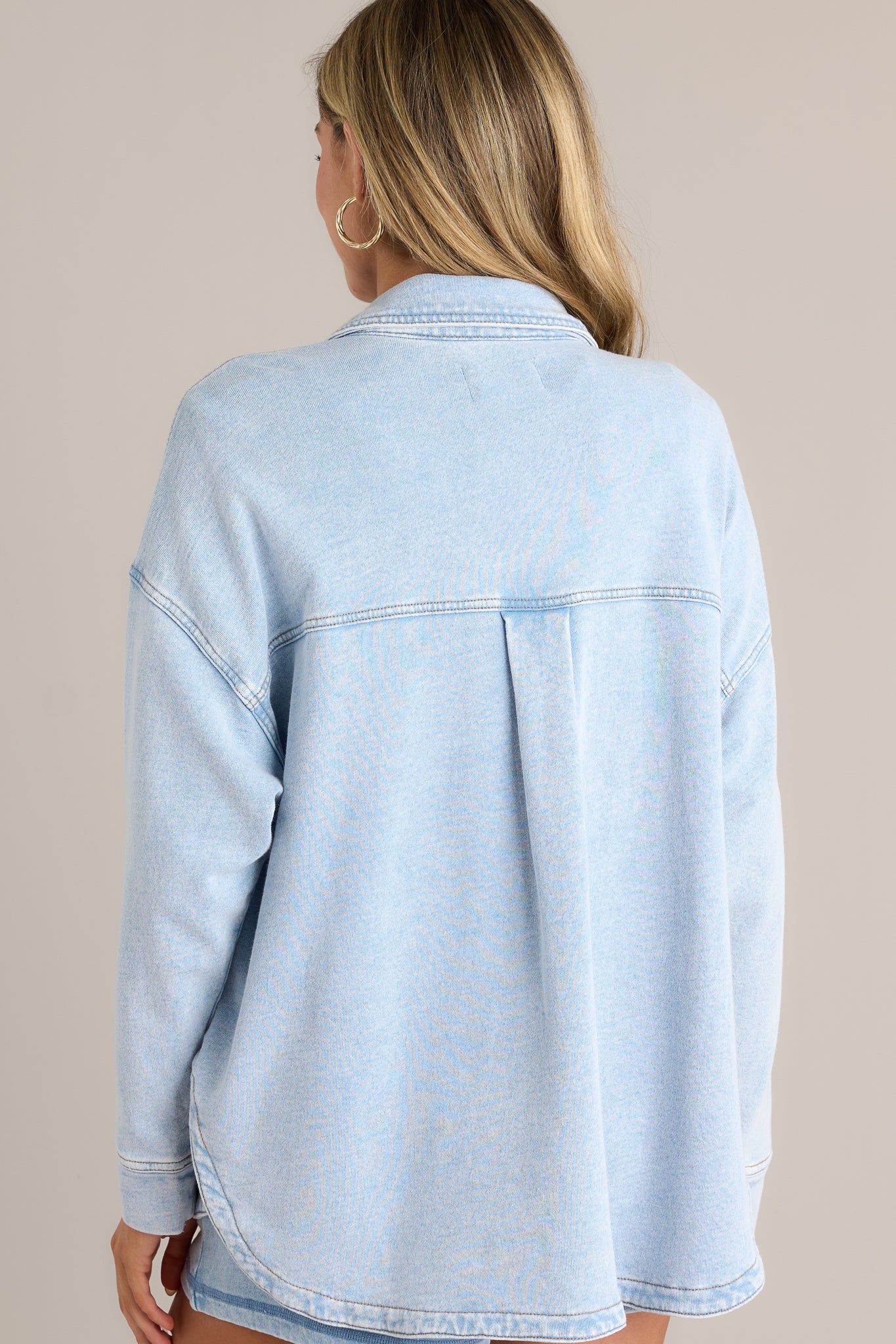 Back view of a denim jacket highlighting the overall fit and curved hemline.