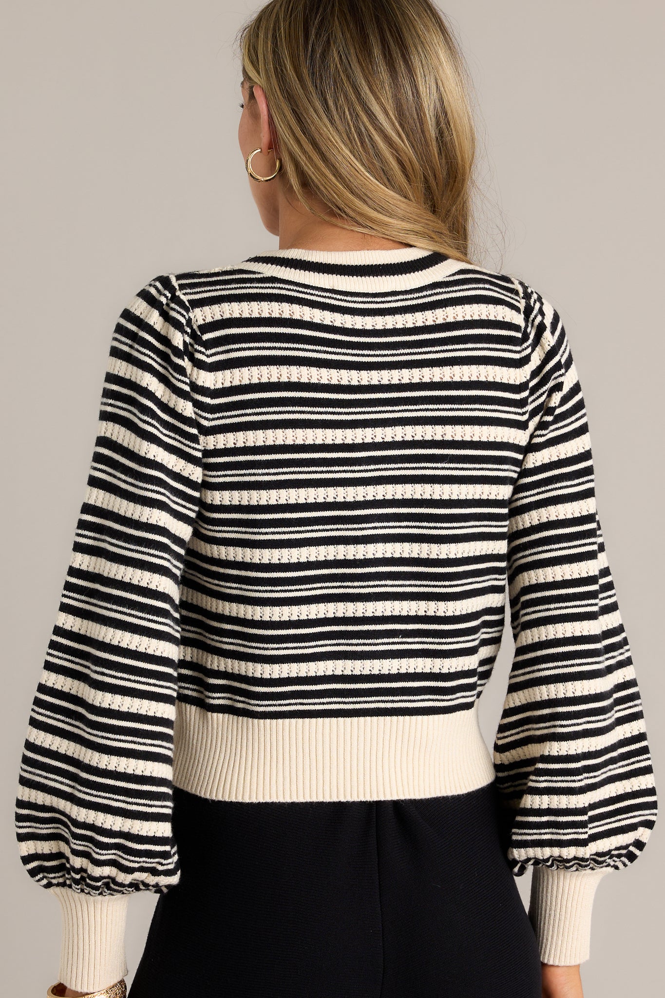 Back view of a stripe sweater top highlighting the overall fit, classic horizontal stripe design, thick hem, and cuffed long sleeves.