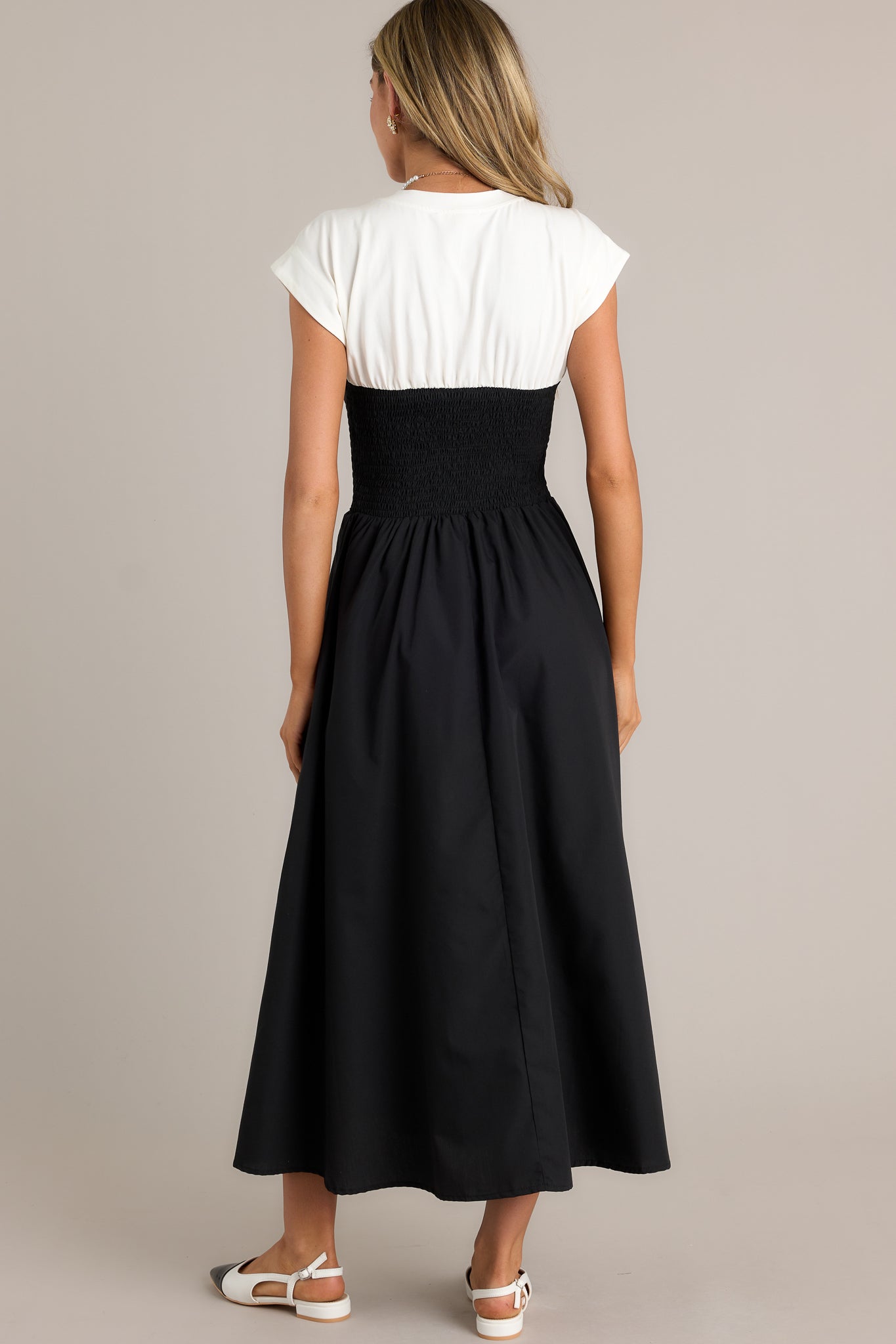 Back view of a black and white dress highlighting the overall fit, smocked waist, and flowing silhouette.