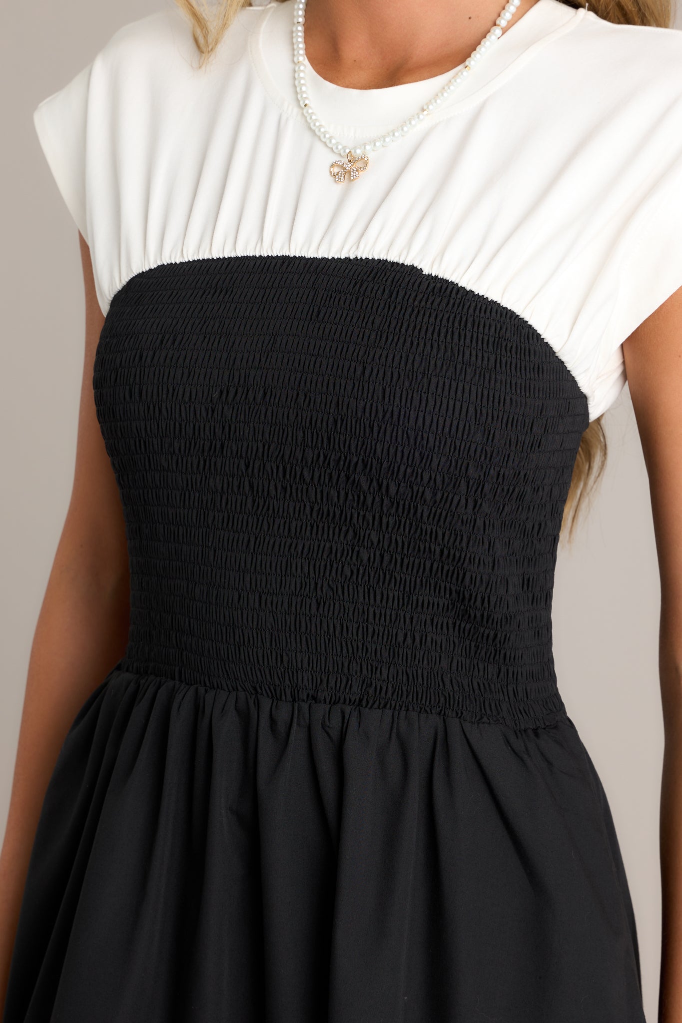 Close-up of the black and white dress showing the round neckline, smocked waist, and white color-blocked top.