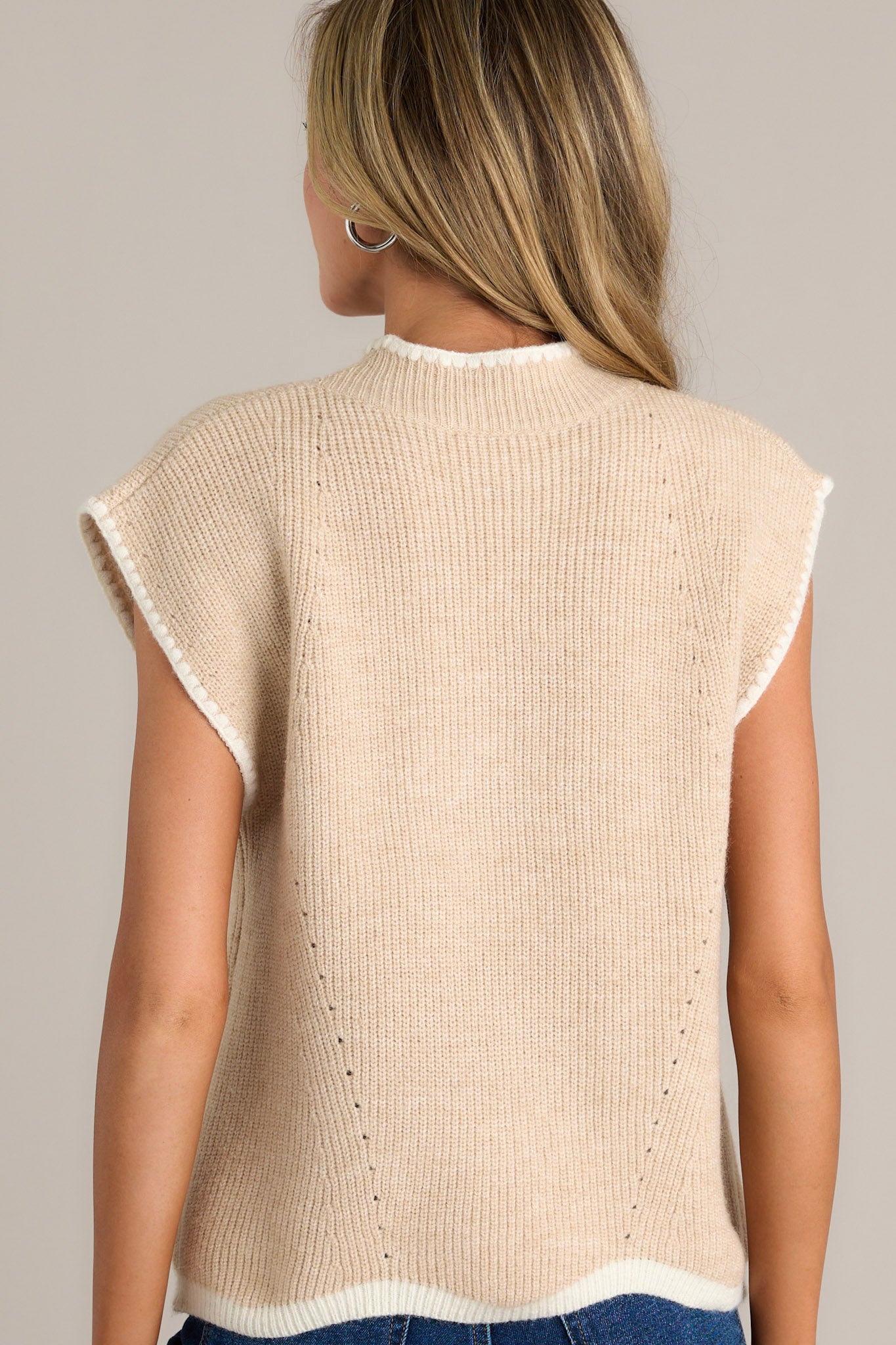 Back view of a beige sweater top highlighting the overall fit, cap sleeves, and soft knitted fabric.