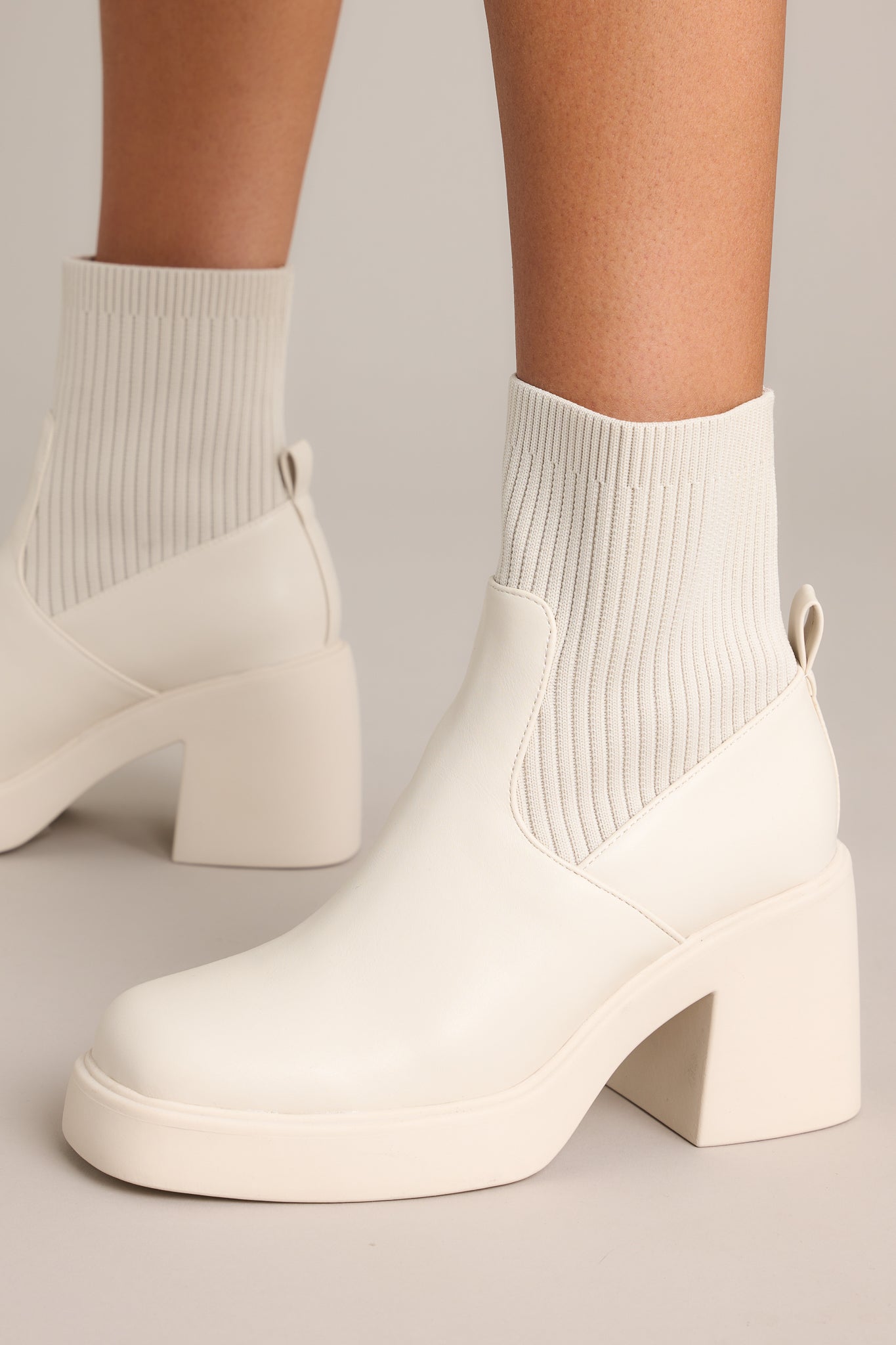 These boots feature a rounded toe, a platform heel, and a stretchy ribbed cloth material around the ankle.