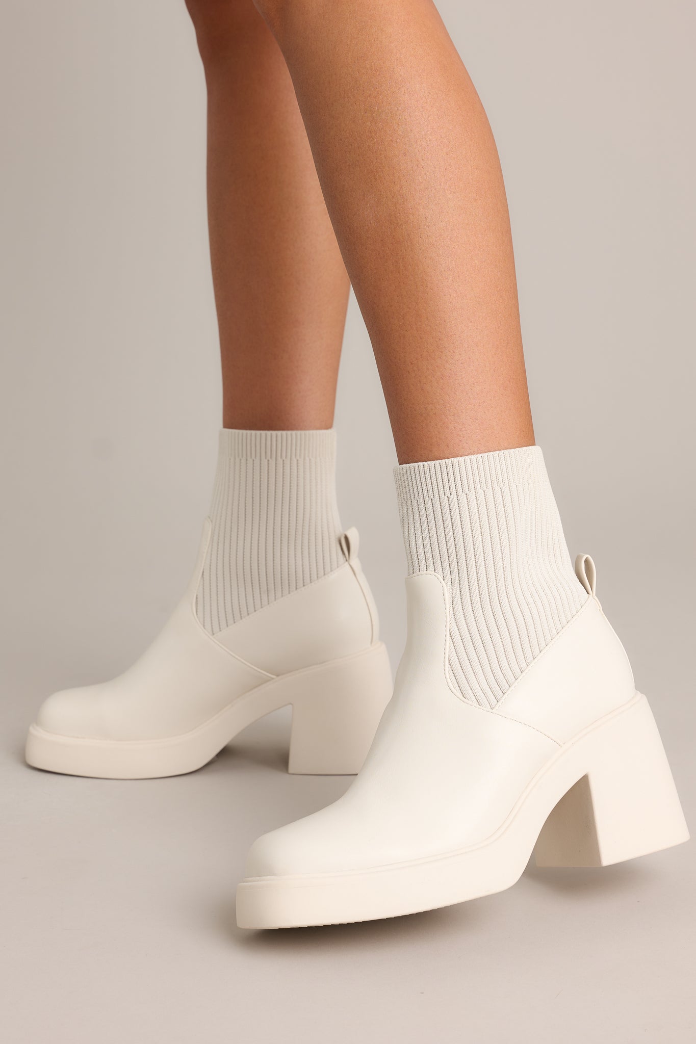 Angled side view of these boots featuring a rounded toe, a platform heel, and a stretchy ribbed cloth material around the ankle.