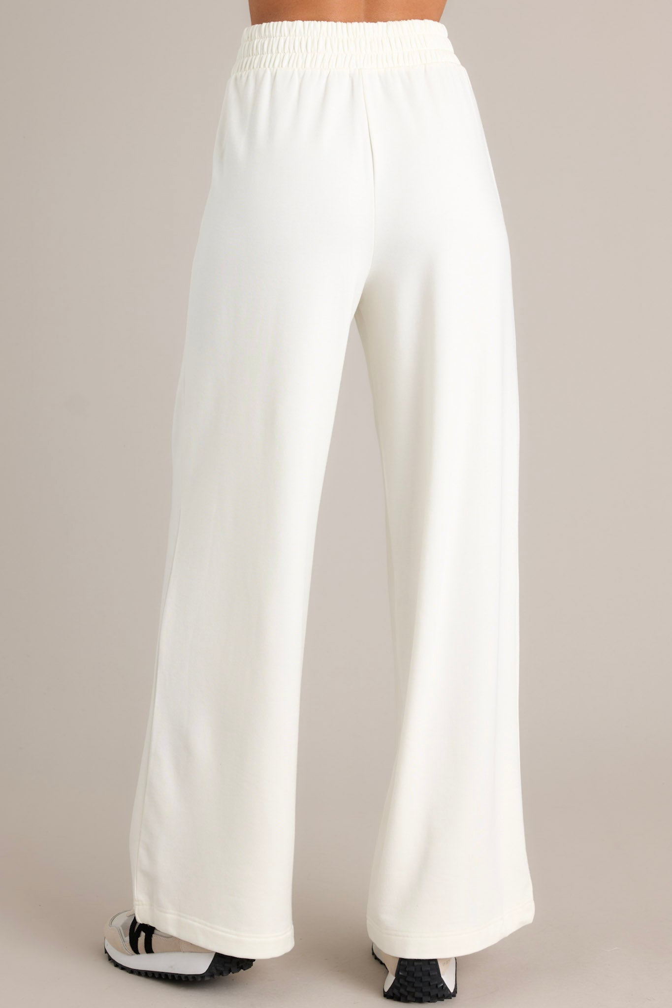 Back view of white fleece pants highlighting the overall fit, elastic waistband, and straight leg.