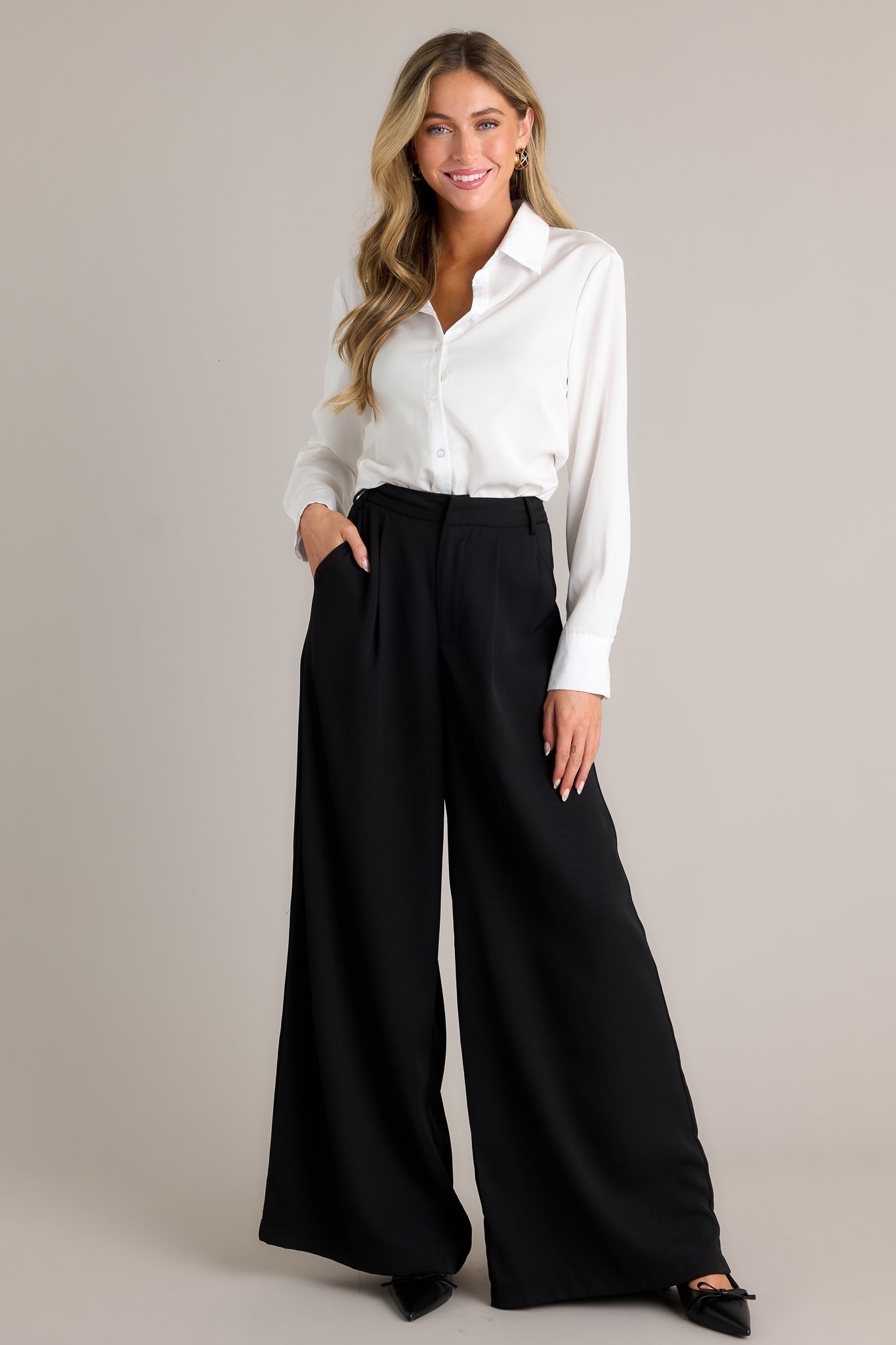 These black pants feature a high waist fit, a hook and bar closure, belt loops, pockets, and a wide leg.