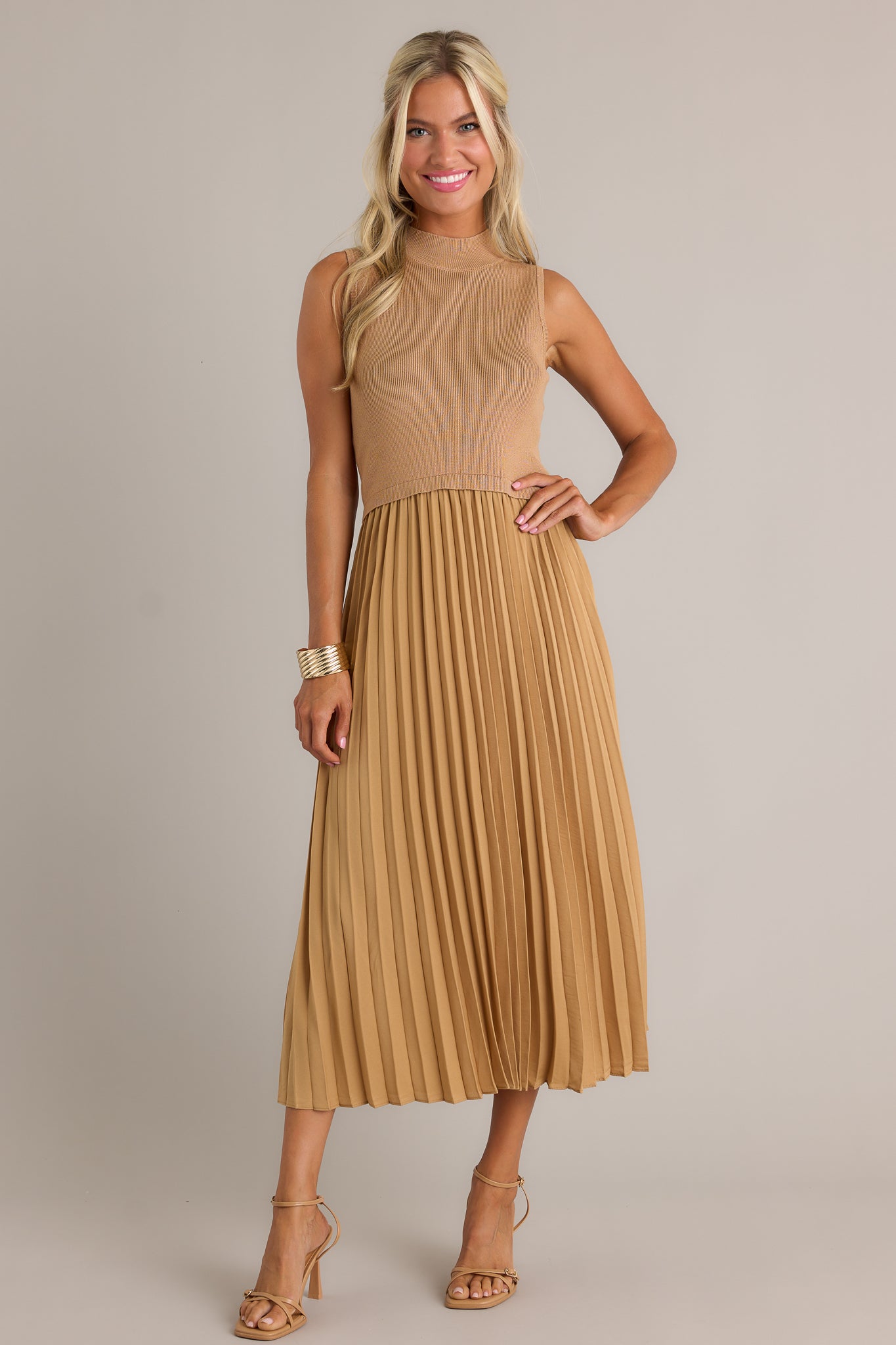 Front view of this mustard sleeveless dress featuring a high neckline, a ribbed knit bodice, a pleated skirt, a sleeveless design and a flowing silhouette.