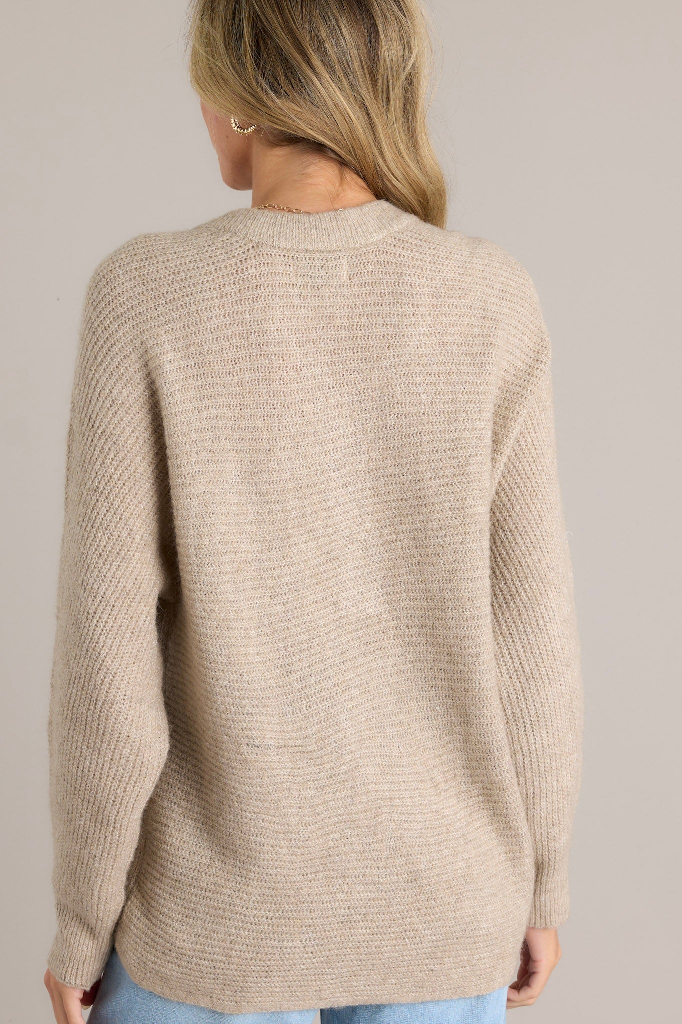 Back view of a sweater highlighting the ribbed detailing and the ruffled long sleeves.