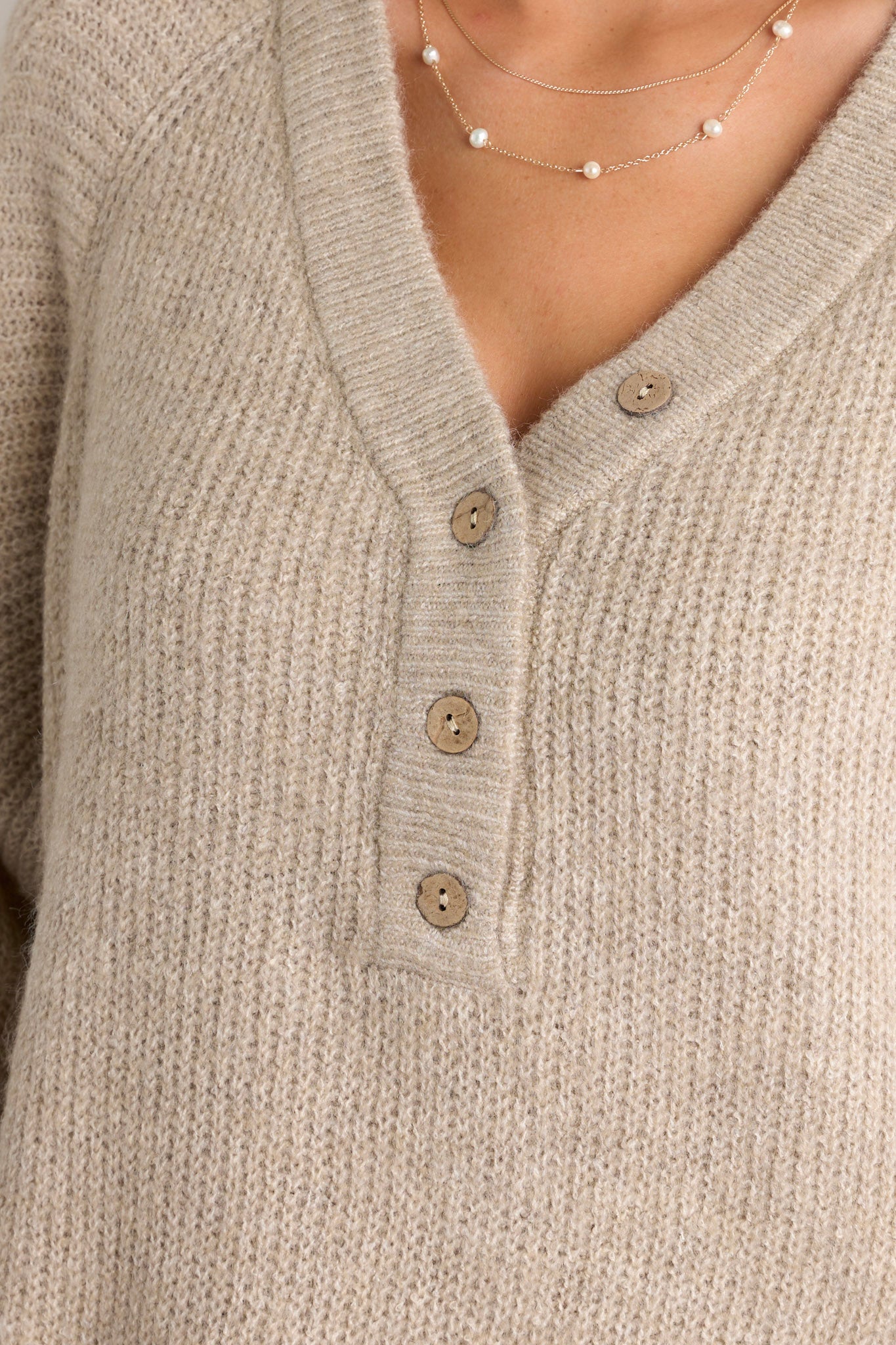 Close-up of the sweater focusing on the v-neckline, functional buttons, and the ribbed ruffled long sleeves