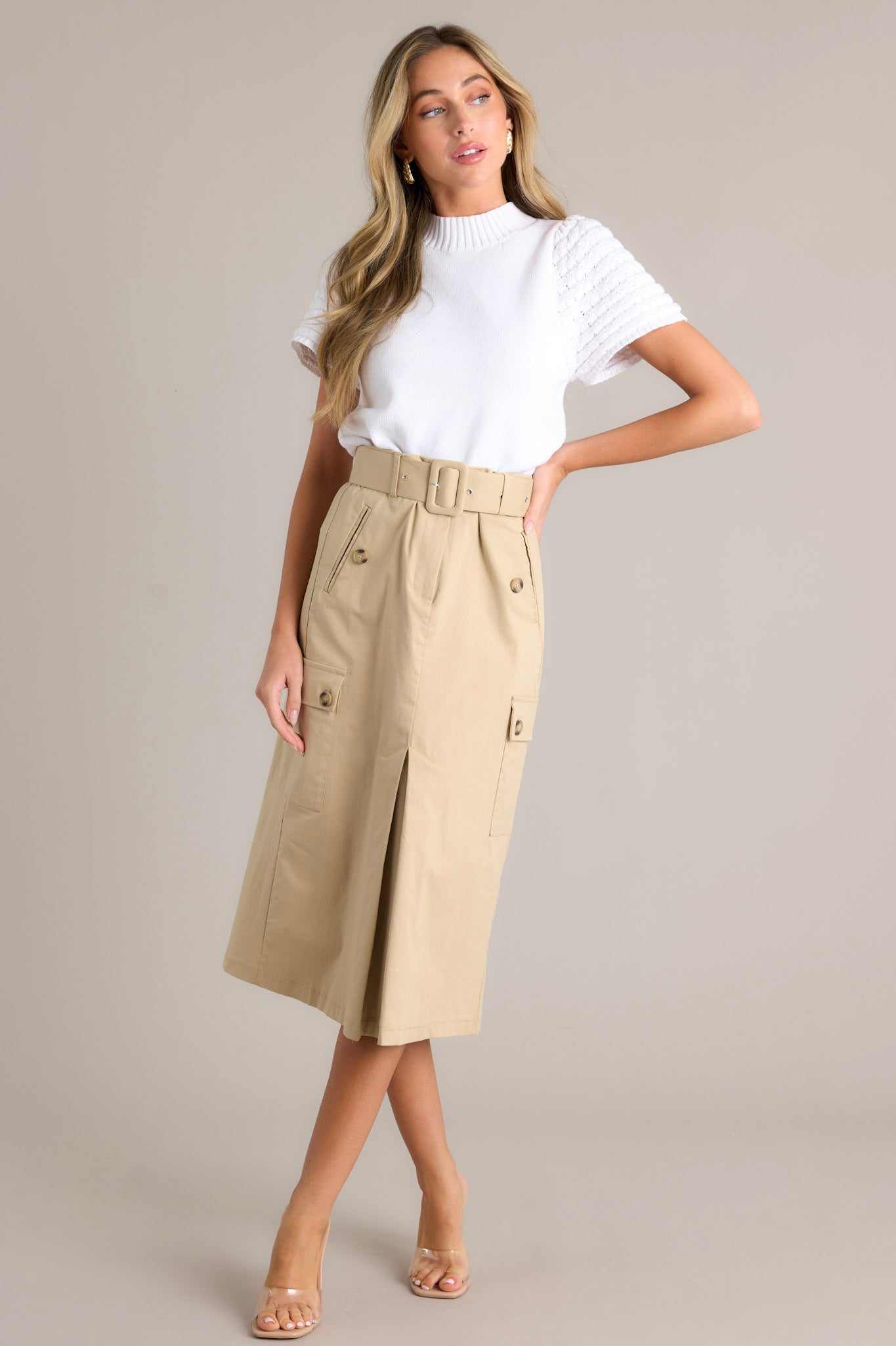 Front angled view of a skirt featuring a high waisted design, a zipper & button closure, belt loops, a functional belt, 4 functional pockets, and a faux slit in the front