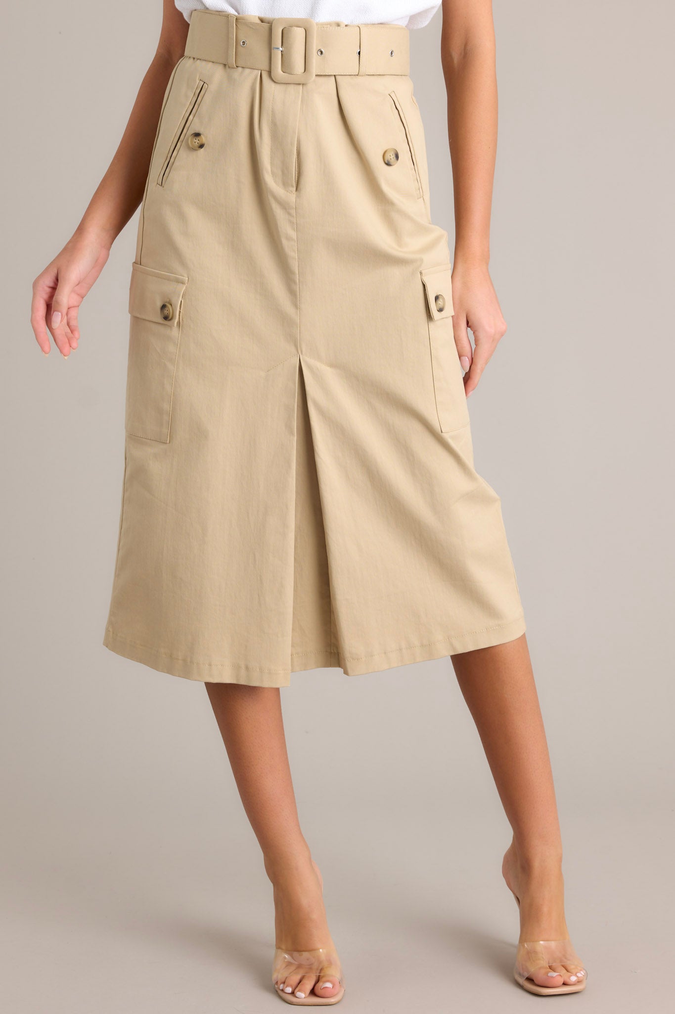 Full length view of a skirt with a high waisted design, a zipper & button closure, belt loops, a functional belt, 4 functional pockets, and a faux slit in the front