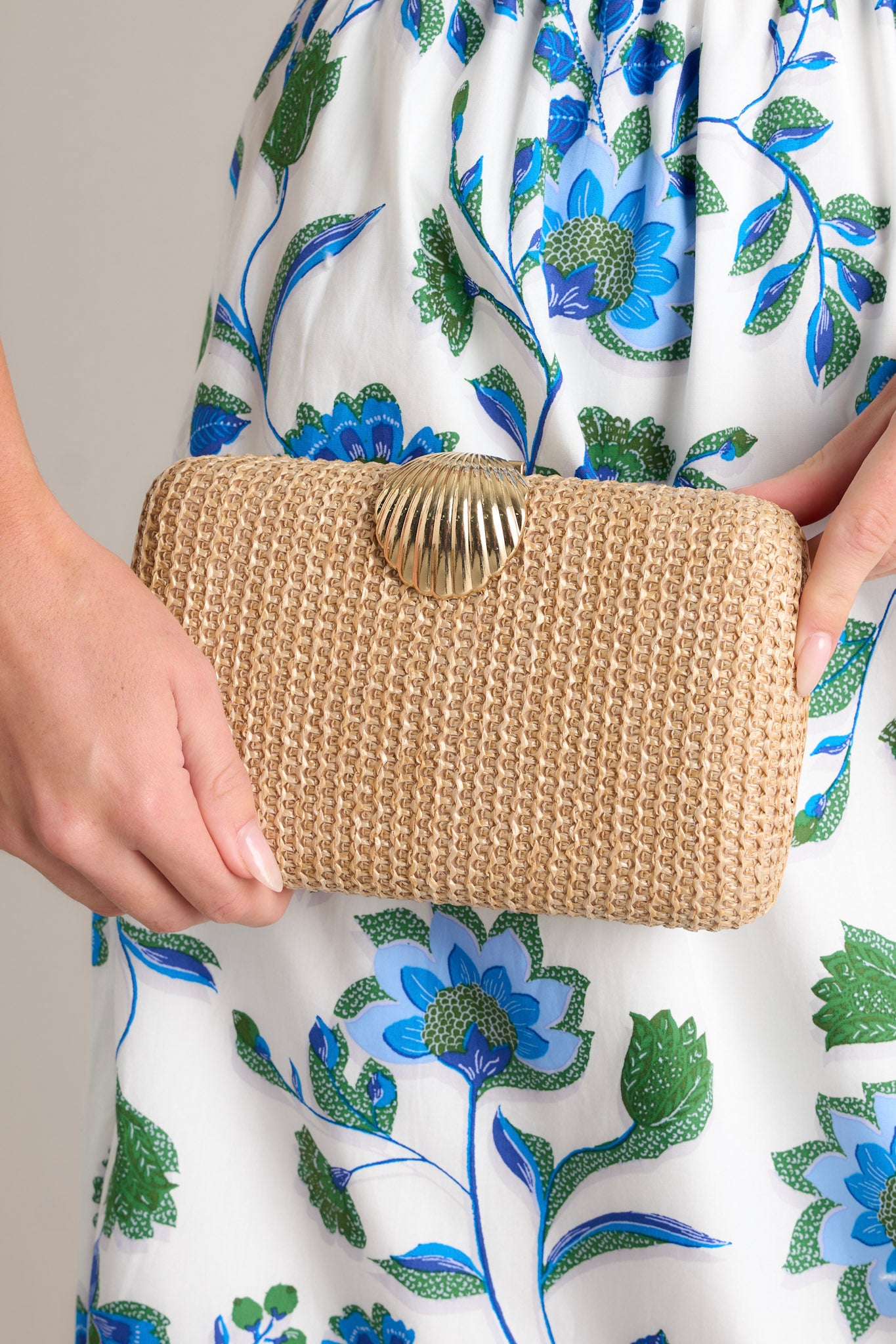 This beige woven clutch features a gold seashell snap closure, two hidden gold clasps for the optional chain, a gold chain and an open interior.