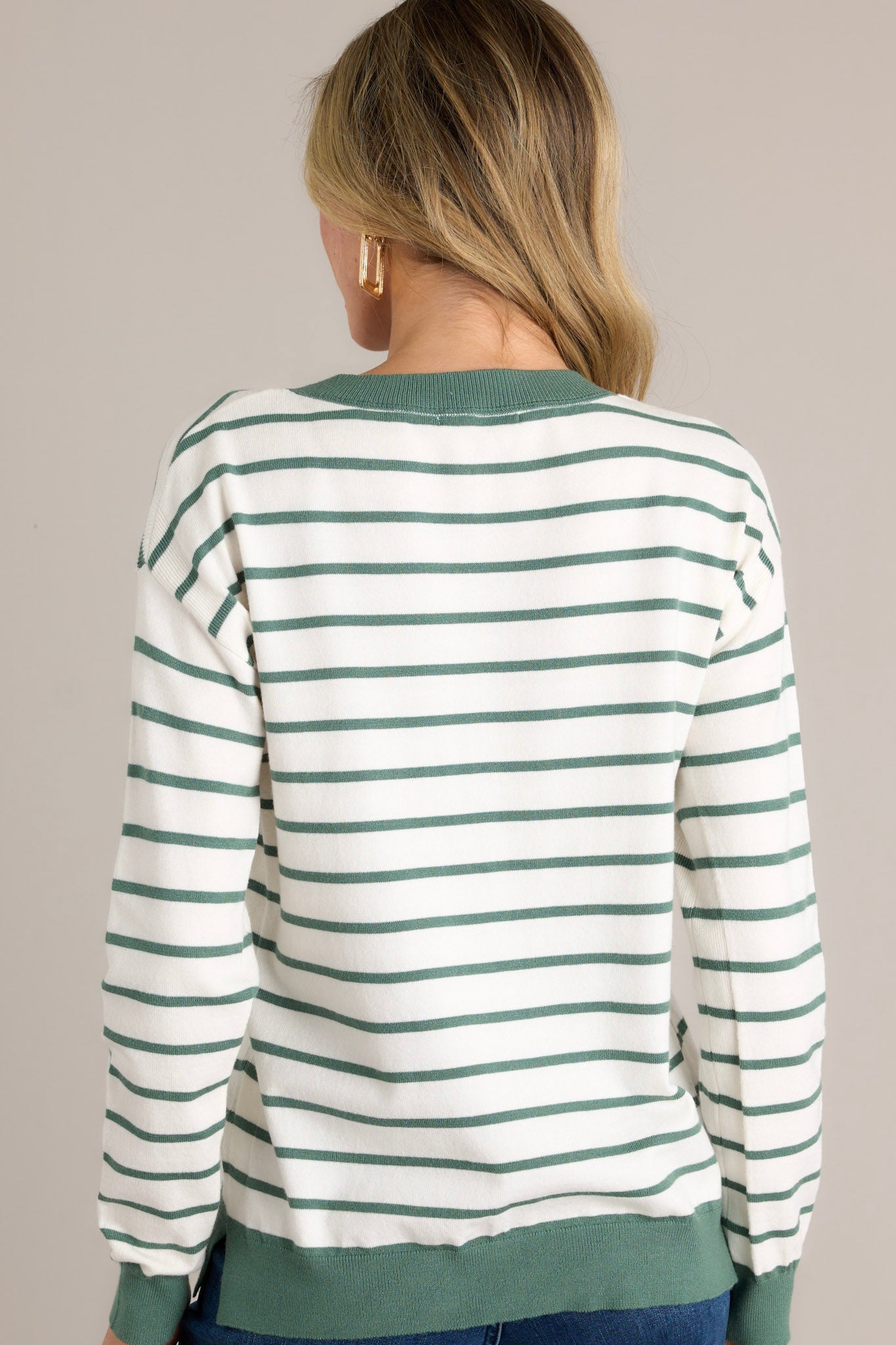 Back view of a striped long sleeve top highlighting the overall fit, green horizontal stripe design, and long cuffed sleeves.