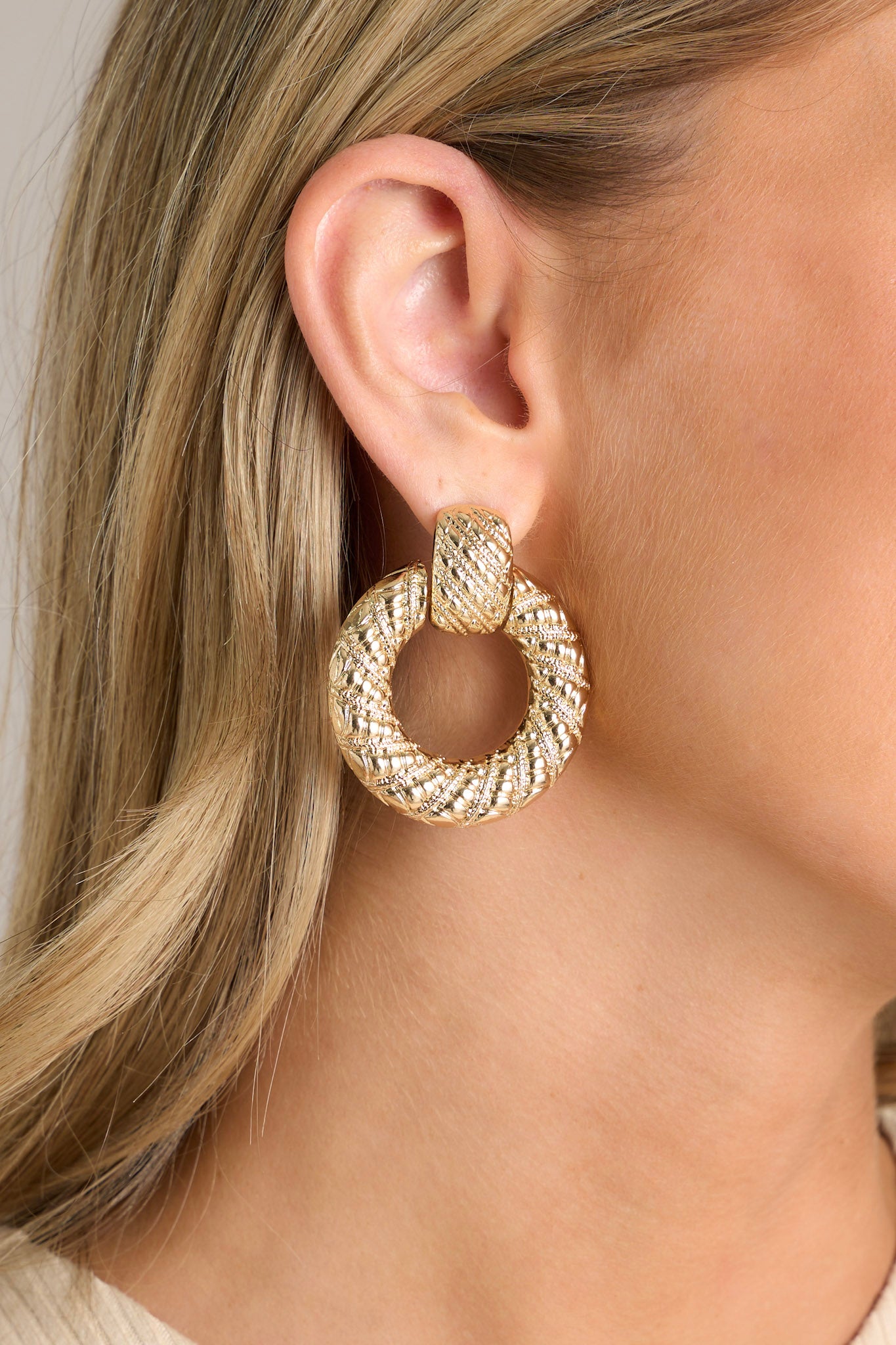 Close-up of these gold earrings that feature a ridged stud with a connected hoop with the ridges increasing in size.