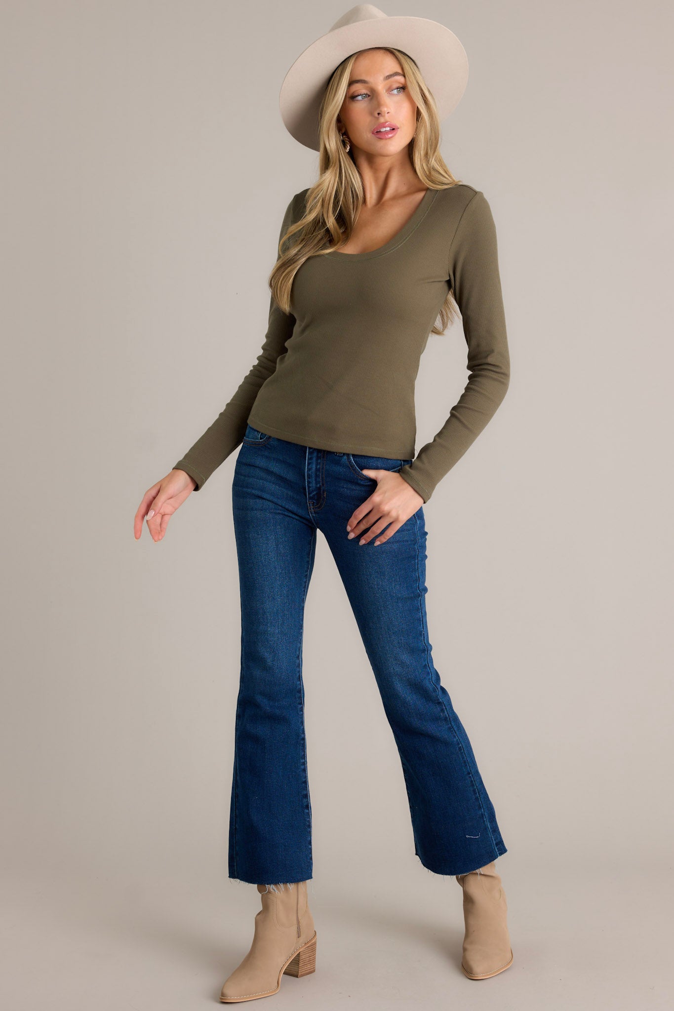 Action shot of a green top displaying the fit and movement, highlighting the scoop neckline, ribbed detailing, and long sleeves.