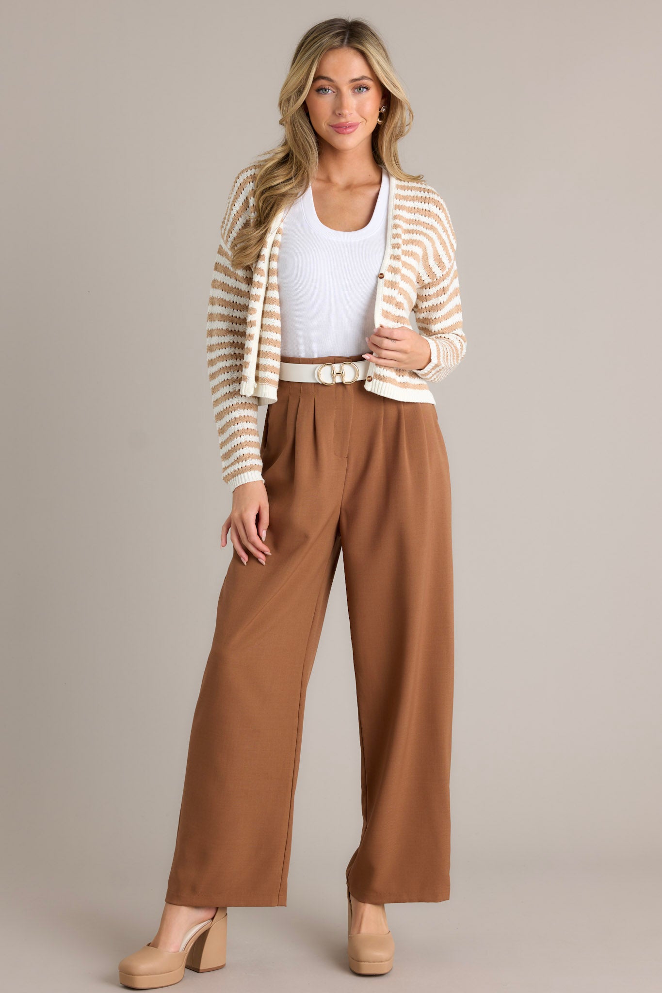 These brown straight leg pants feature a high waisted design, a button zipper closure, slight pleats, functional hip pockets and a straight leg.