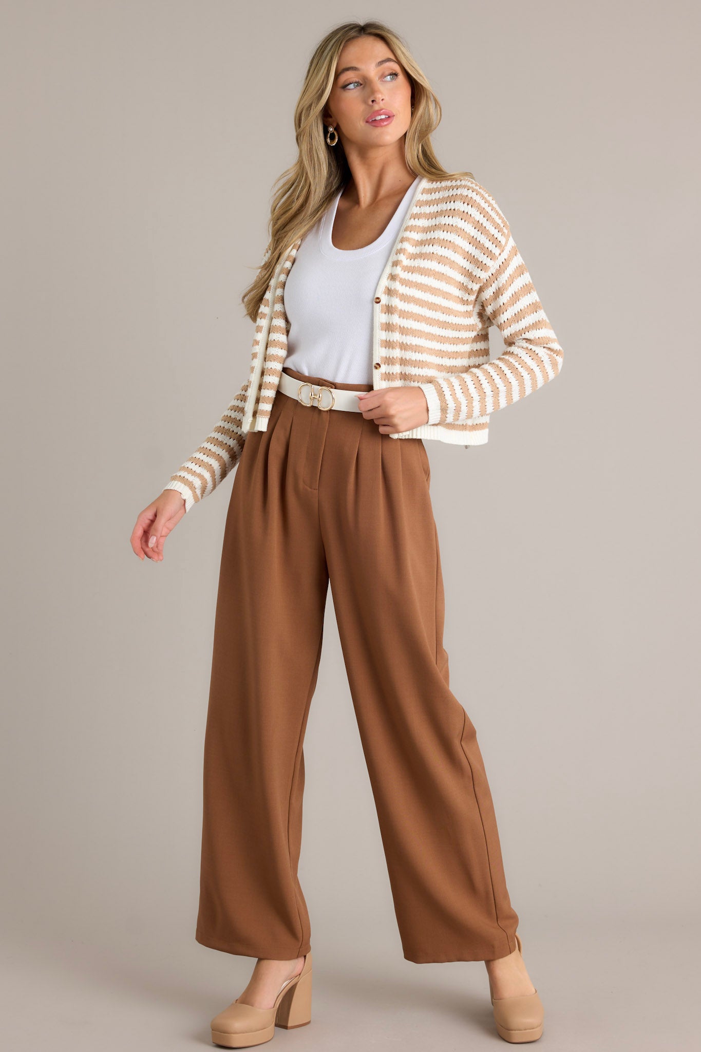 Full length view of brown straight leg pants with a high waisted design, a button zipper closure, slight pleats, functional hip pockets, and a straight leg,