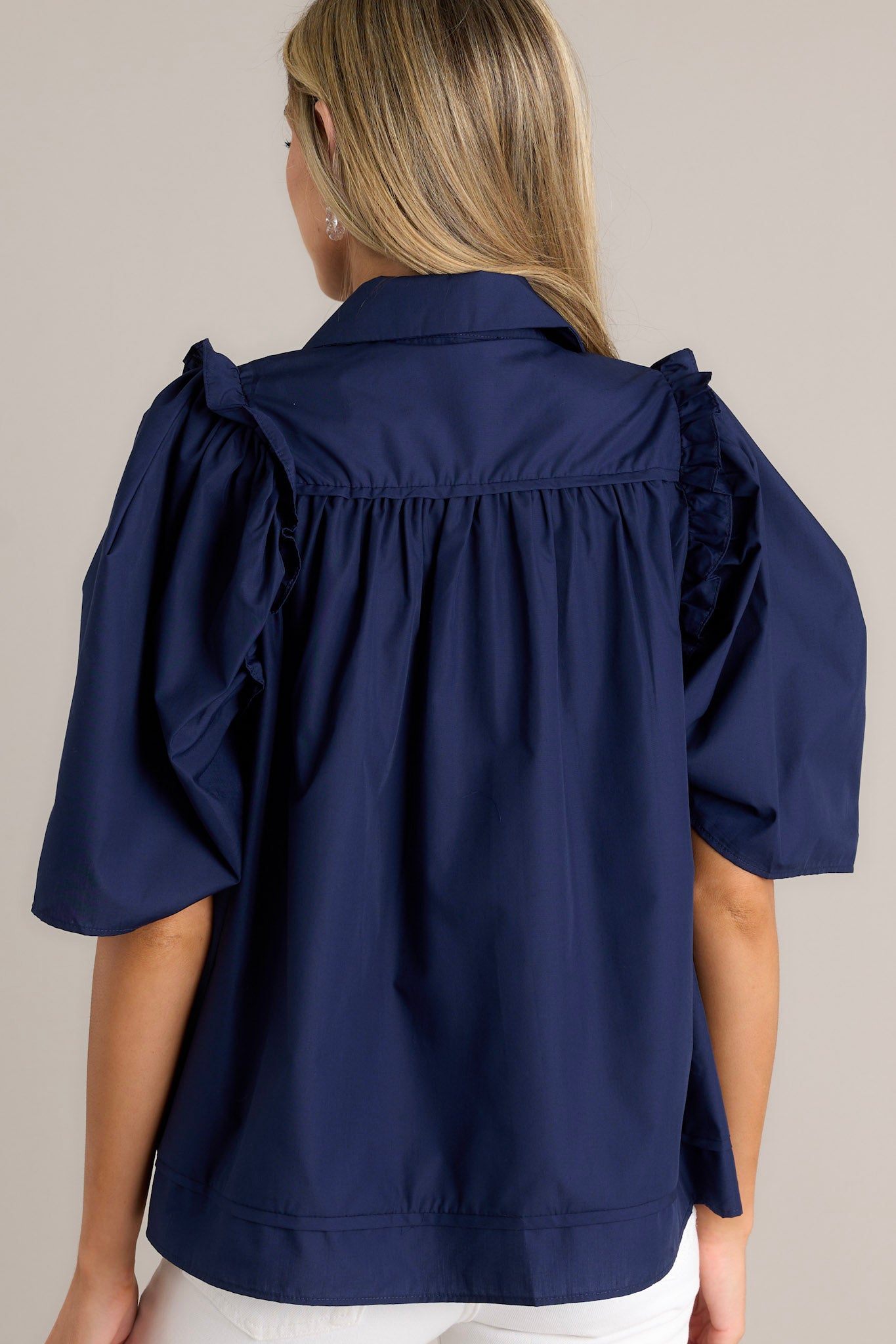 Back view of a navy top highlighting the butterfly short sleeves and ruffle detailing.