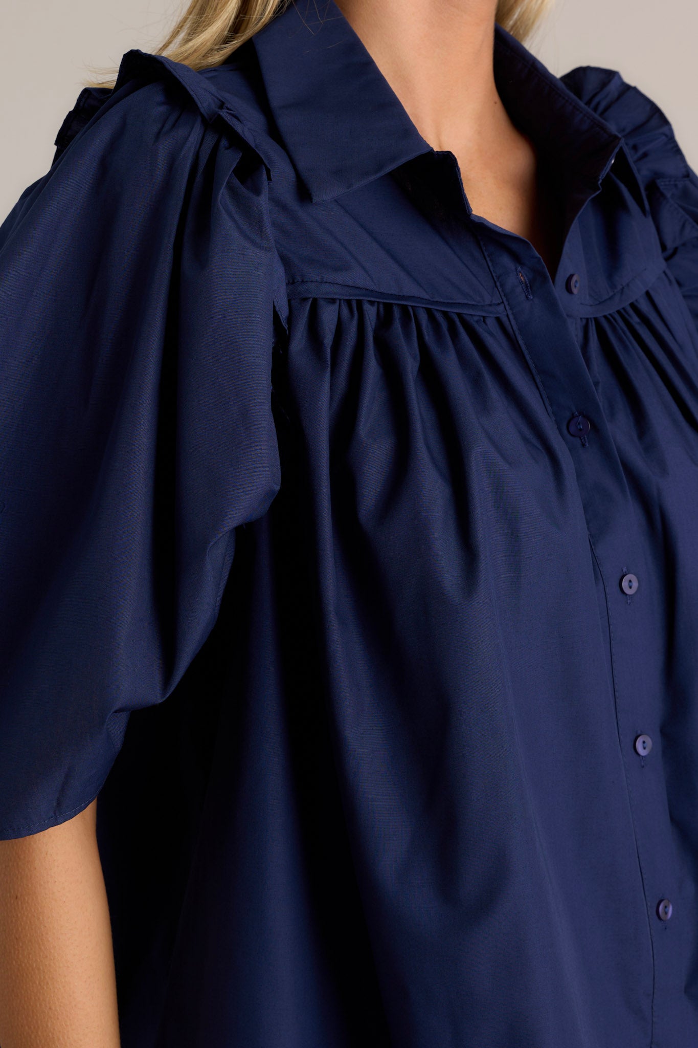 Close-up view of a navy top highlighting the butterfly short sleeves and ruffle detailing.