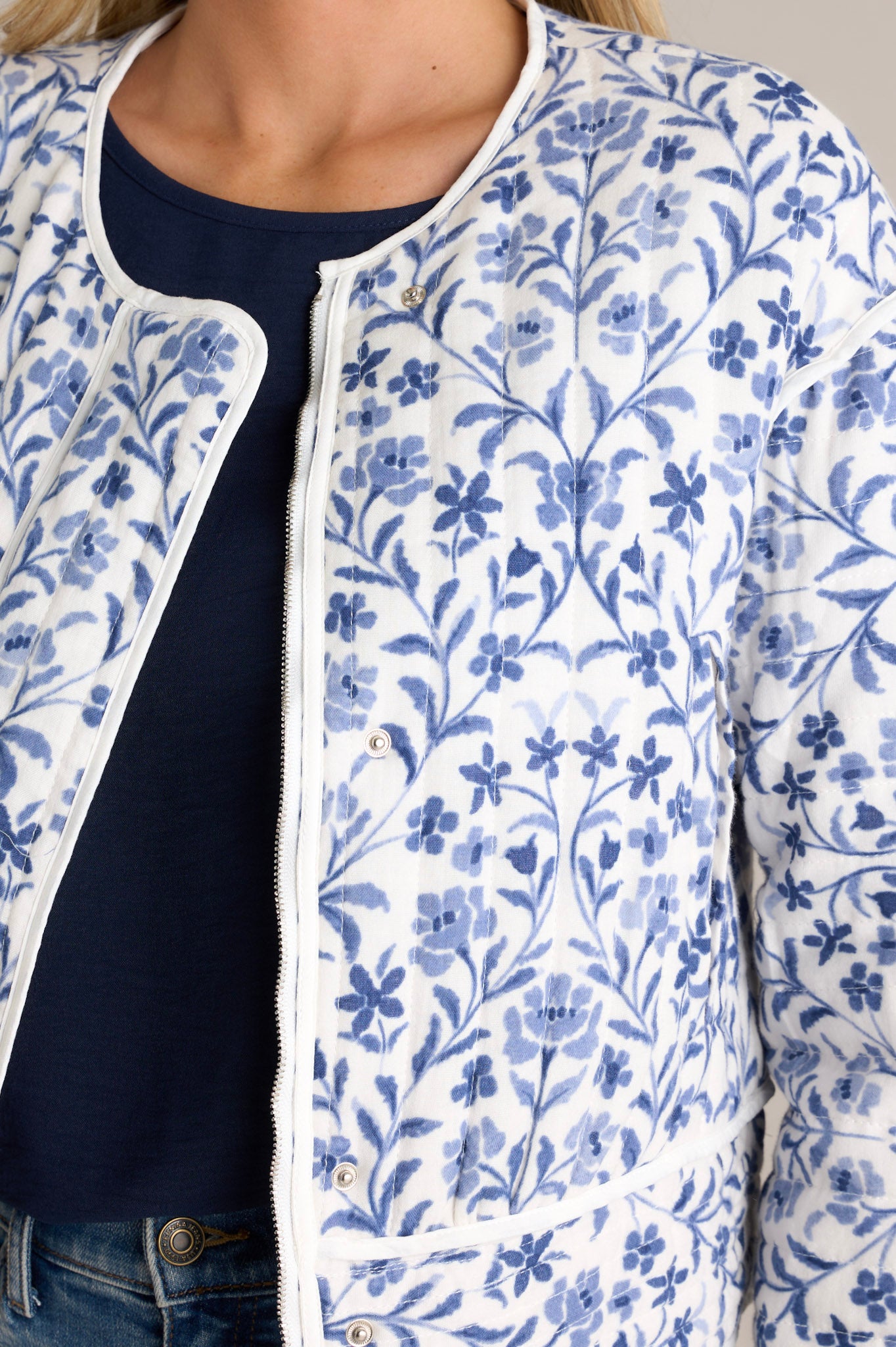 Close-up of a blue jacket showing the fun floral print, the hidden zipper, and the front buttons.