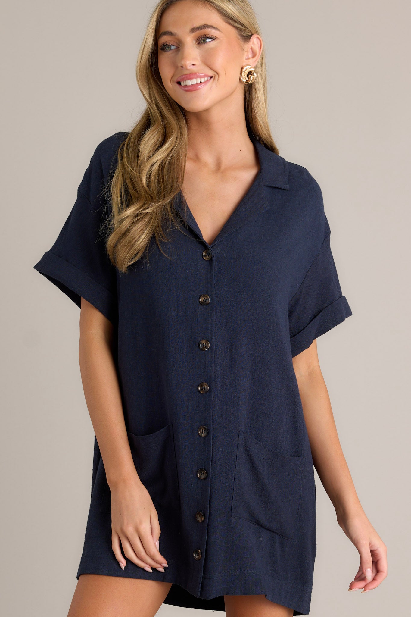 Navy button-down dress with short cuffed sleeves, a collared neckline, and functional pockets for a comfy, casual style.