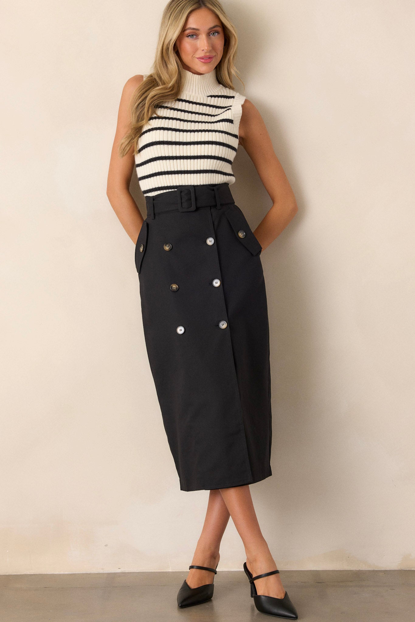 This black maxi skirt features a high waisted design, an elastic waist insert, a square fabric belt, functional hip pockets, functional front buttons and an open leg.