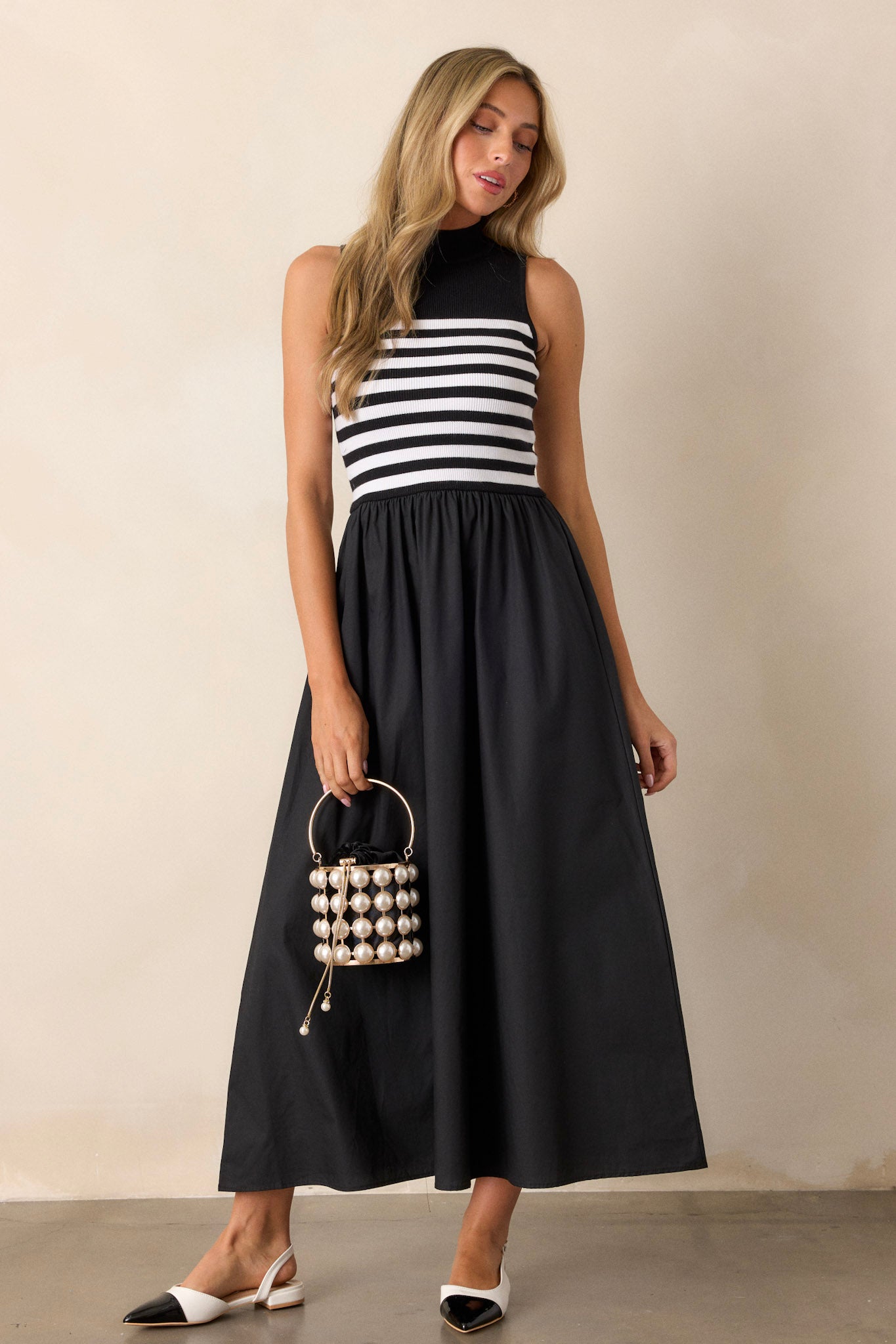 This black stipe maxi dress features a high neckline, a striped sweater bodice, and a flowy skirt.