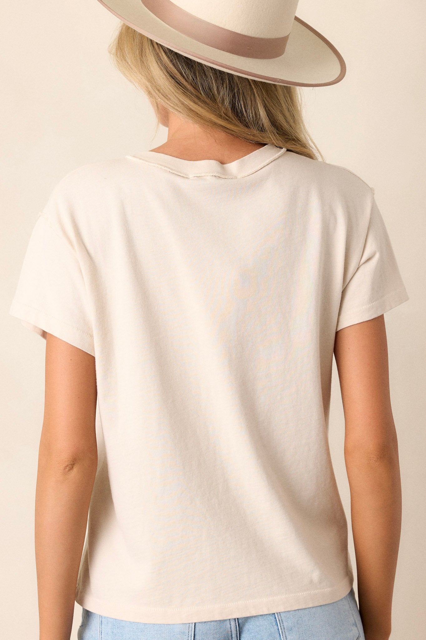 Back view of the beige tee highlighting the raw hemline and the smooth, breathable cotton fabric.