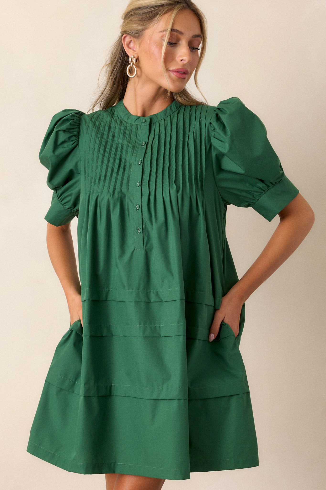 Front angled view of the dress featuring two side pockets, a functional button-front, and puff sleeves