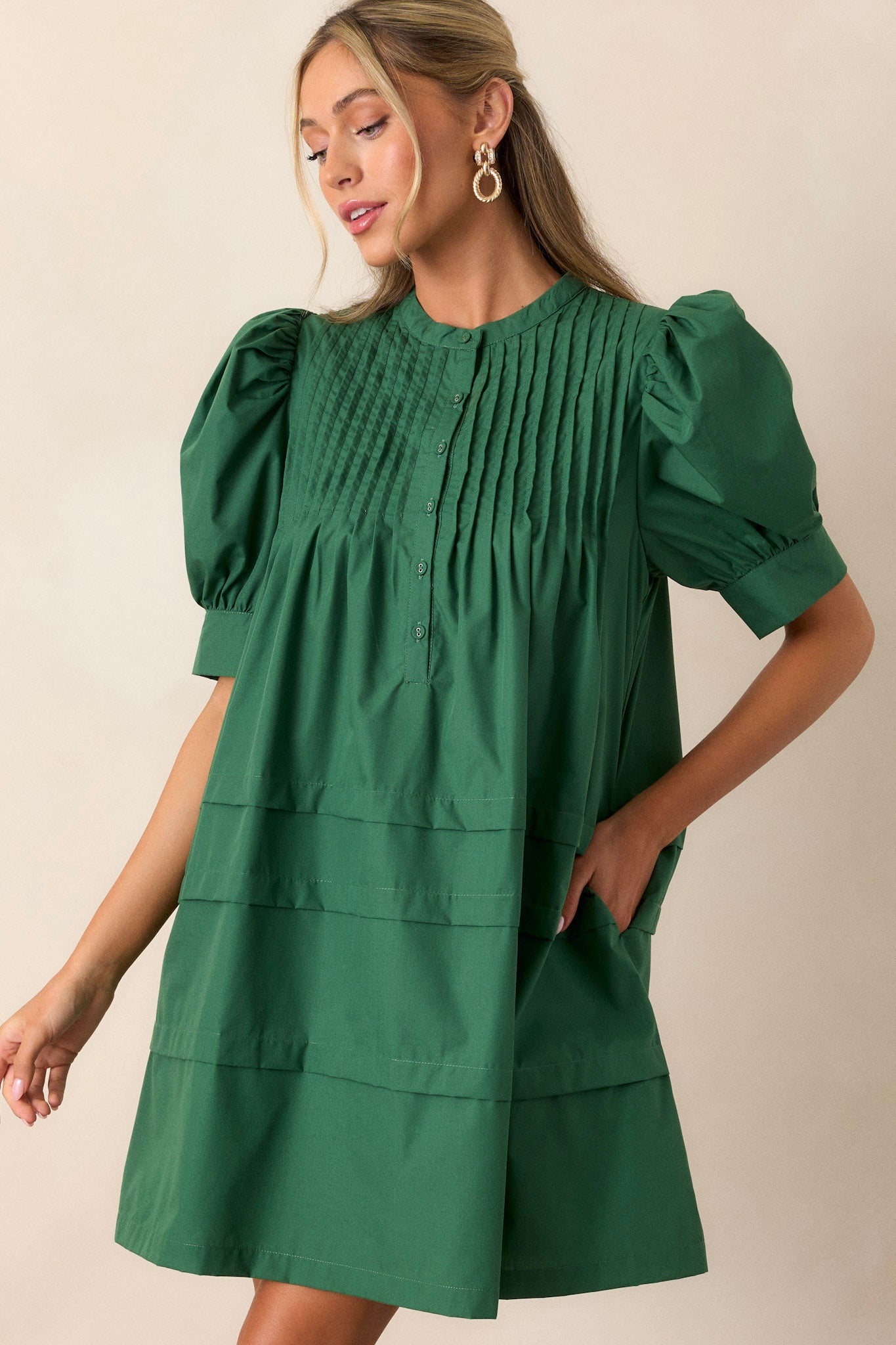 Front view of a dress featuring two side pockets, a functional button-front, and puff sleeves.