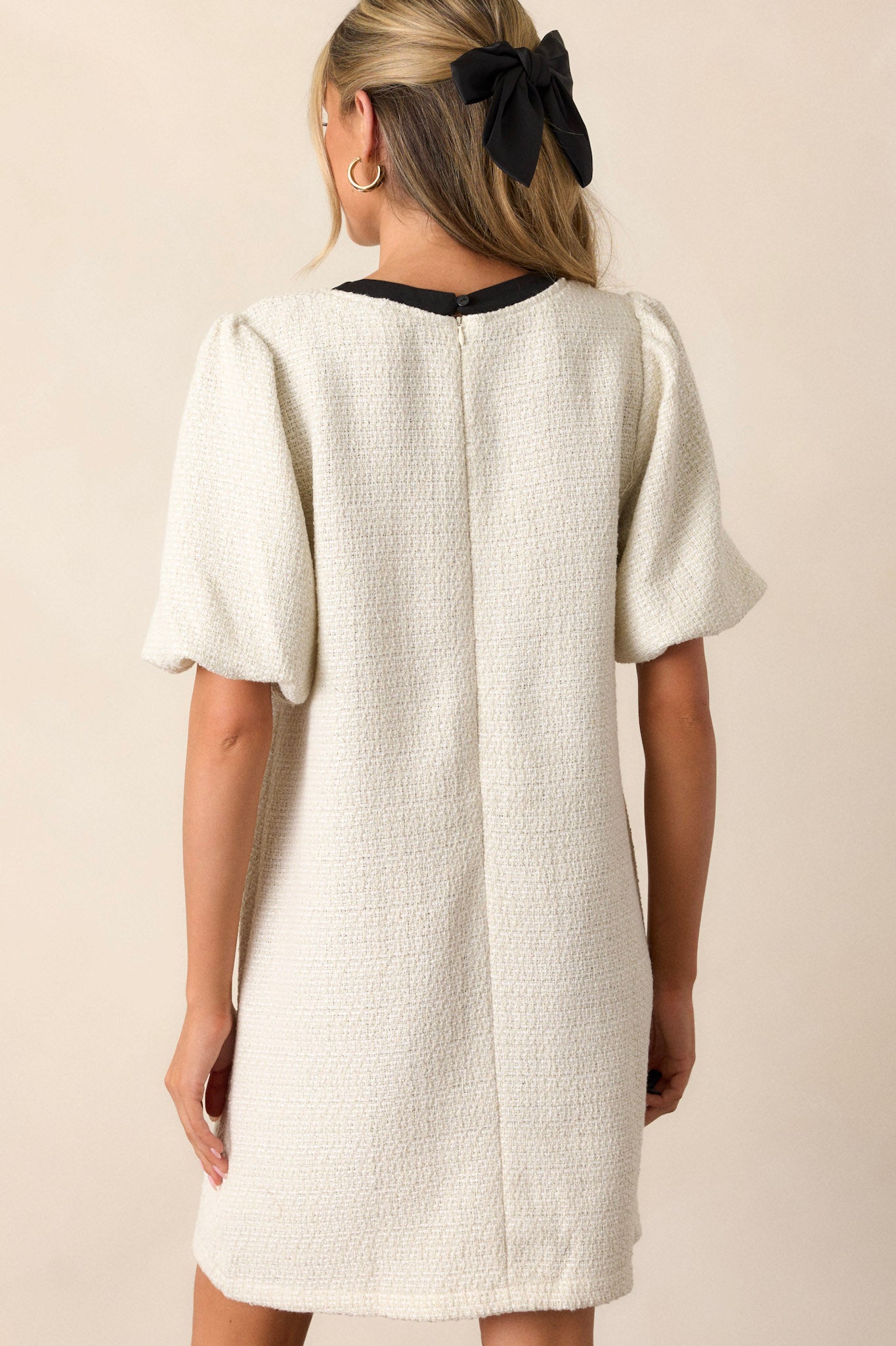 Back view of the ivory tweed dress showcasing the discrete back zipper and the overall relaxed fit of the dress, along with a subtle view of the elastic cuffed short sleeves.