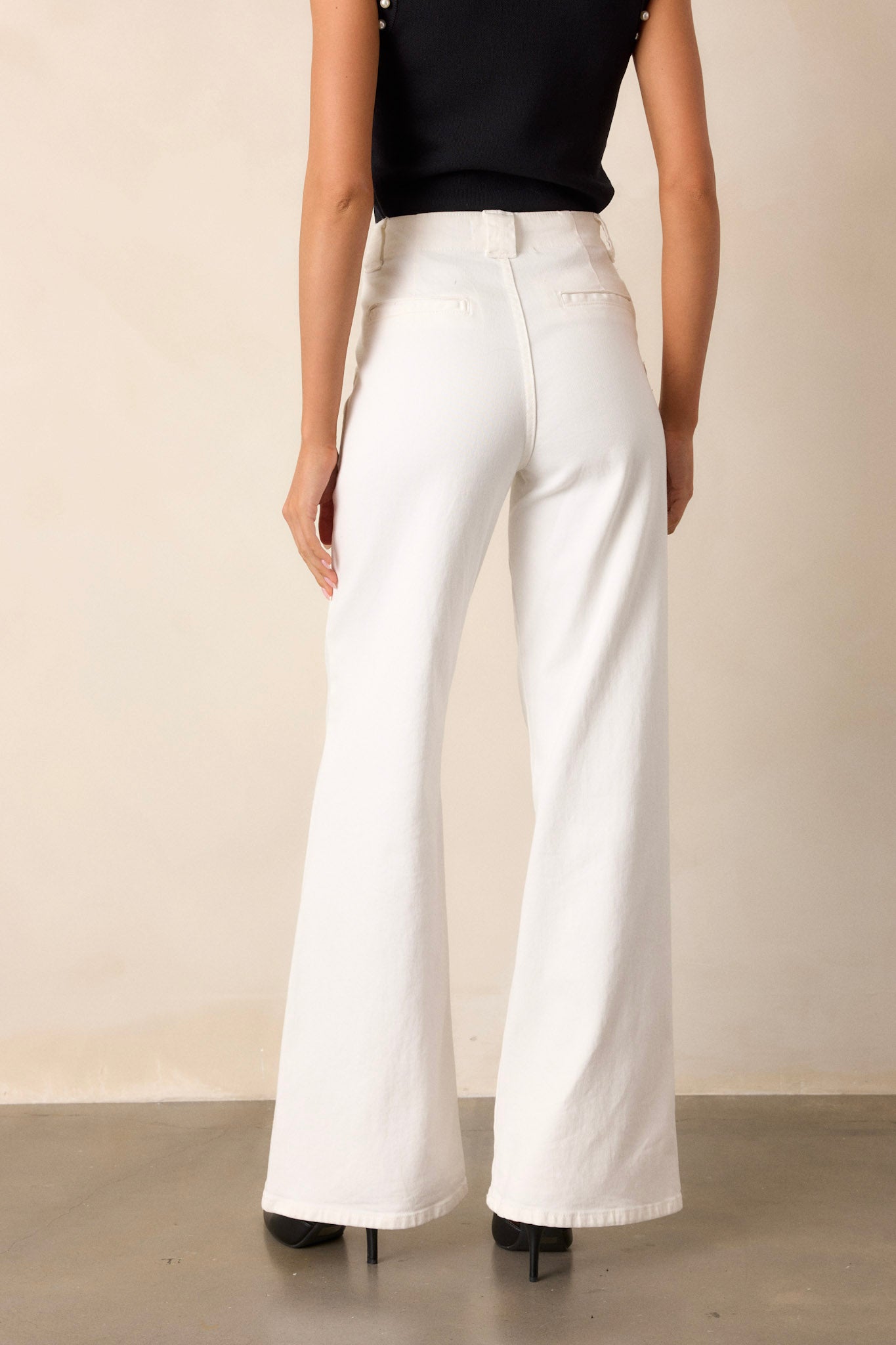 Back view of these white jeans that feature a high waisted design, classic button & zipper closure, belt loops, functional front patch pockets, and a flare leg.