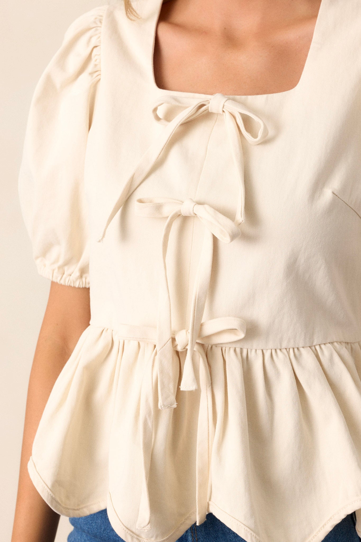 Close-up of the ivory top focusing on the intricate tie front bows, the puff sleeves, and the side zipper.