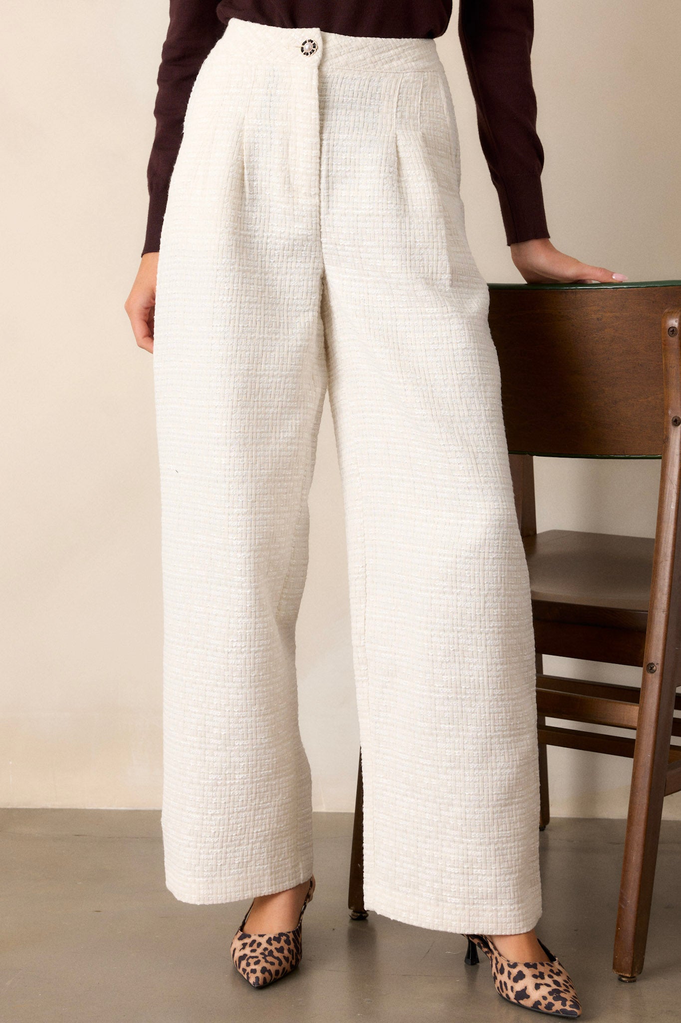 A focused view of the pleated detailing, showcasing how it adds depth and dimension to the design of the ivory pants.