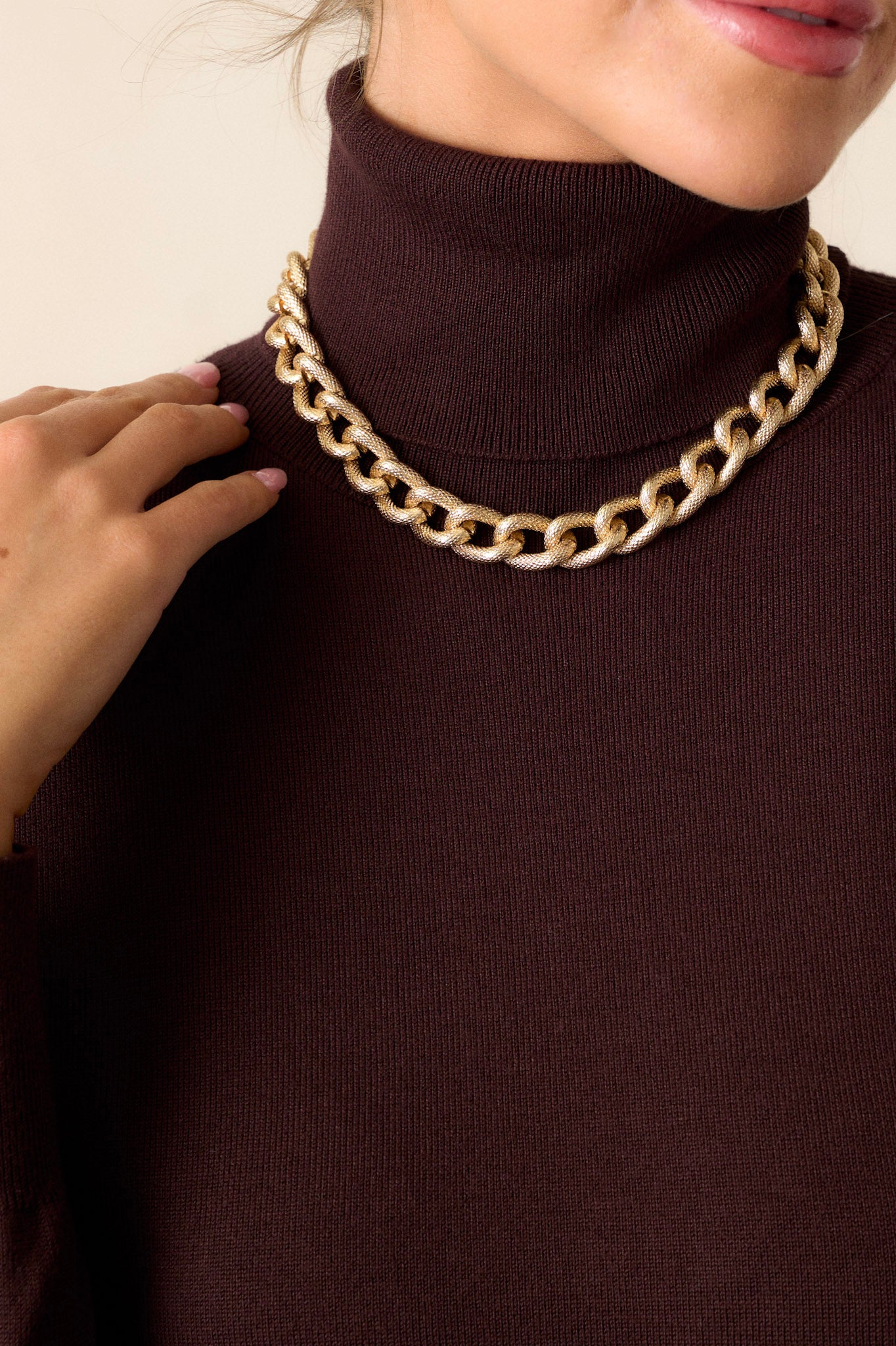 This gold necklace features a curb chain design, matte finish, textured material, and a lobster claw closure.