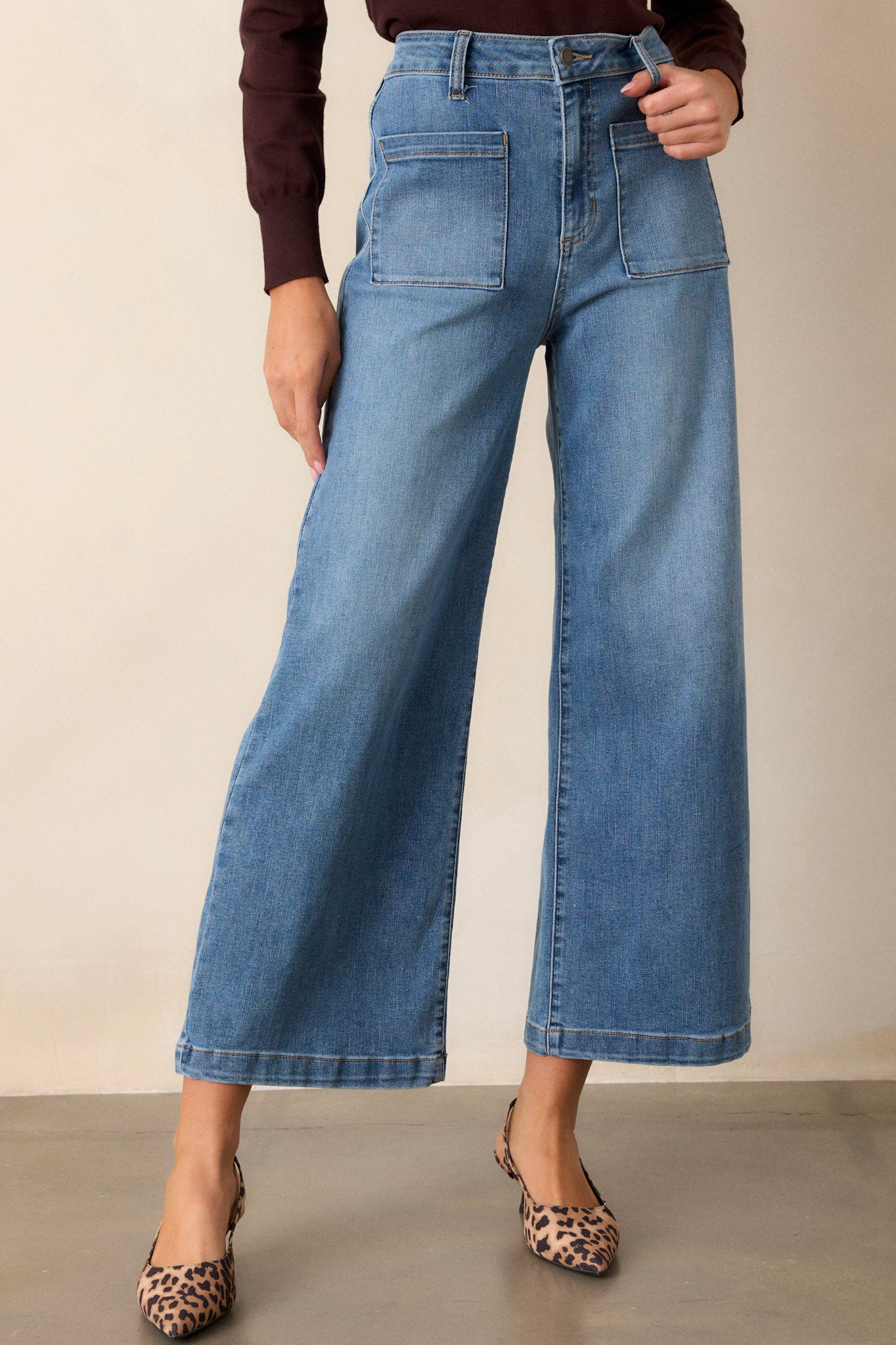 Front view of medium wash jeans featuring functional belt loops, a button zipper closure, functional front and back pockets, and a wide leg design.