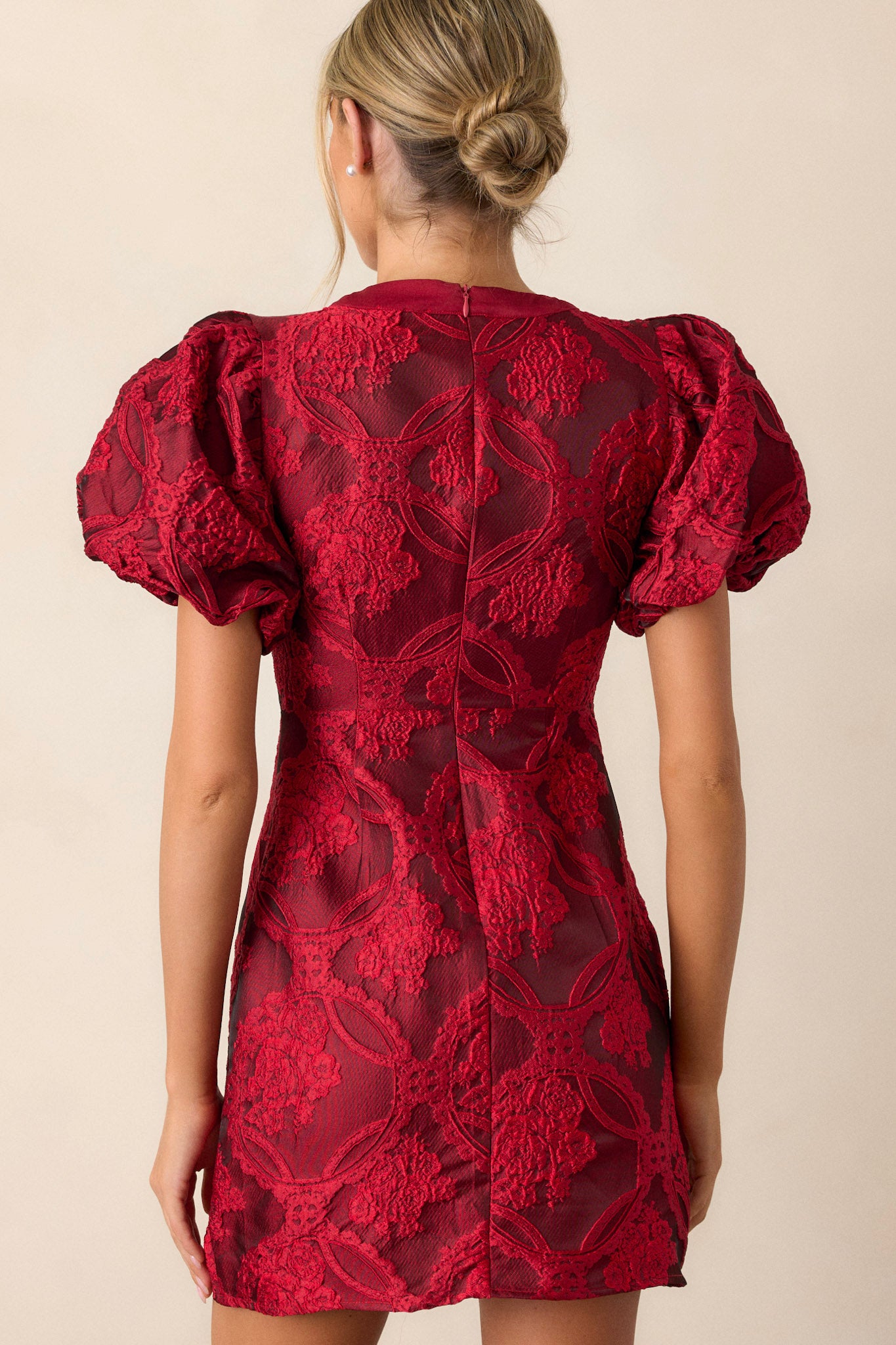 Back view of the berry red dress highlighting the discrete back zipper and the elegant fit of the dress, with a subtle view of the short puff sleeves